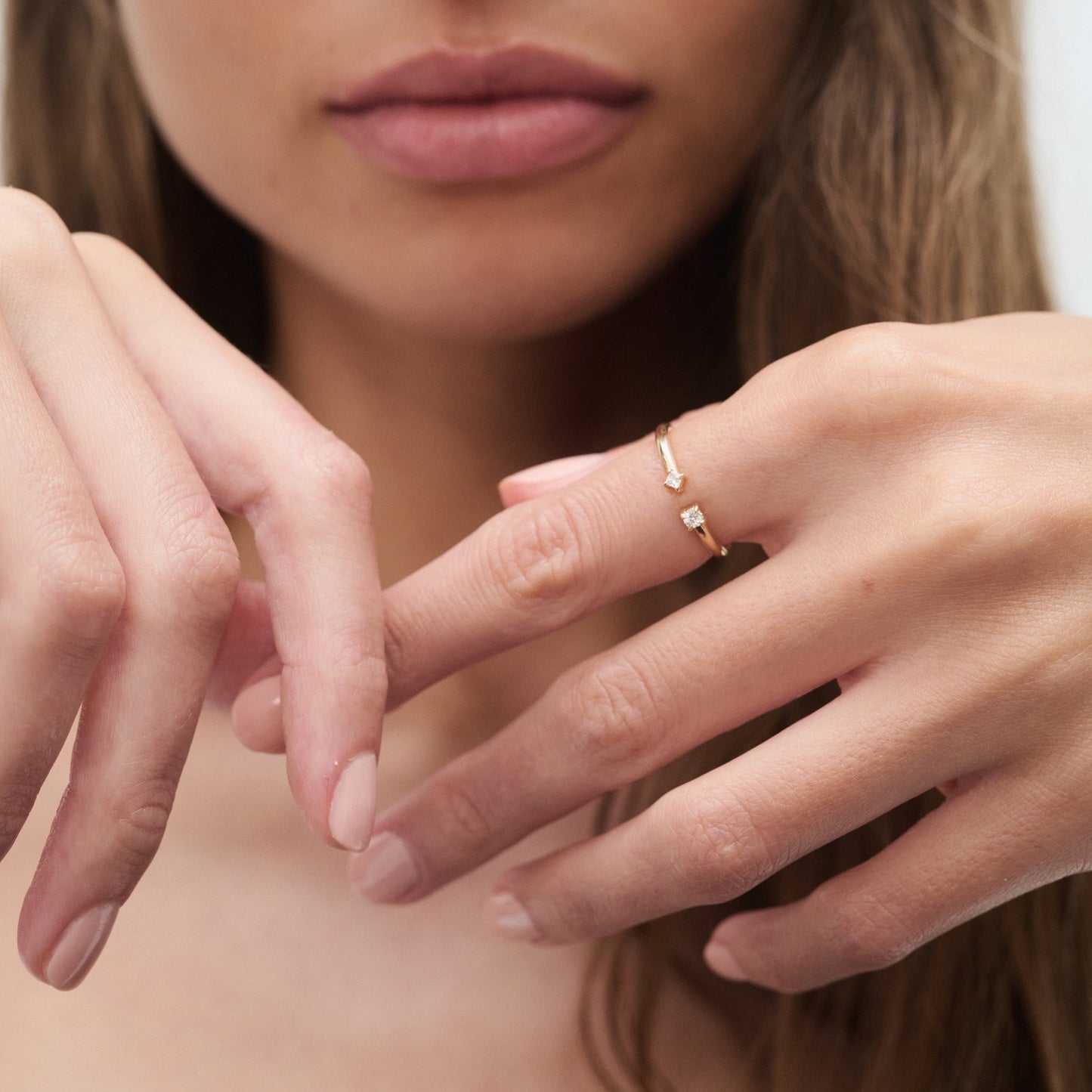 Close-up of a woman’s hands showcasing a delicate gold ring with small stones. The ring is elegantly worn, highlighting luxury jewellery.