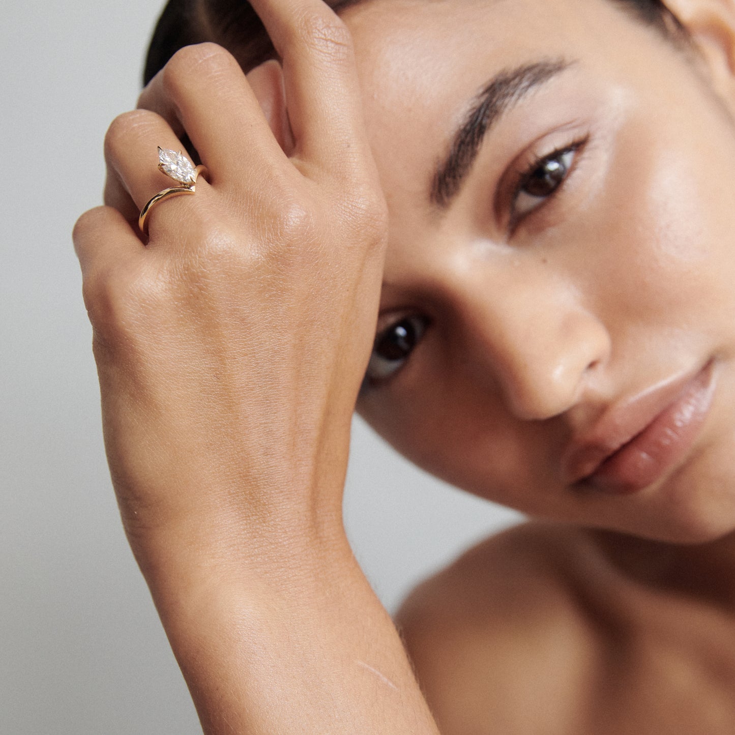 Woman displaying a luxury marquise diamond ring against her face, showcasing fine jewellery craftsmanship in a soft, elegant portrait.
