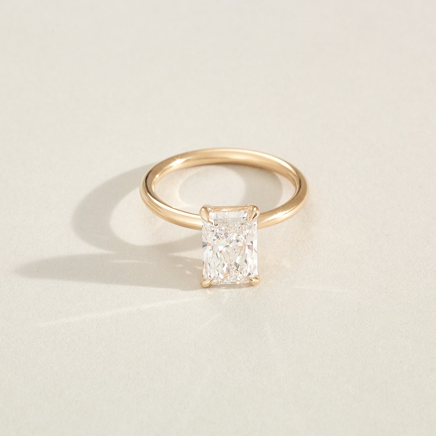 Gold ring with a square-cut diamond on a light beige background