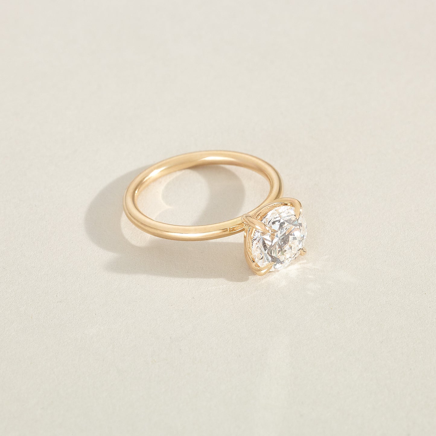 Gold ring with a diamond on a light beige background