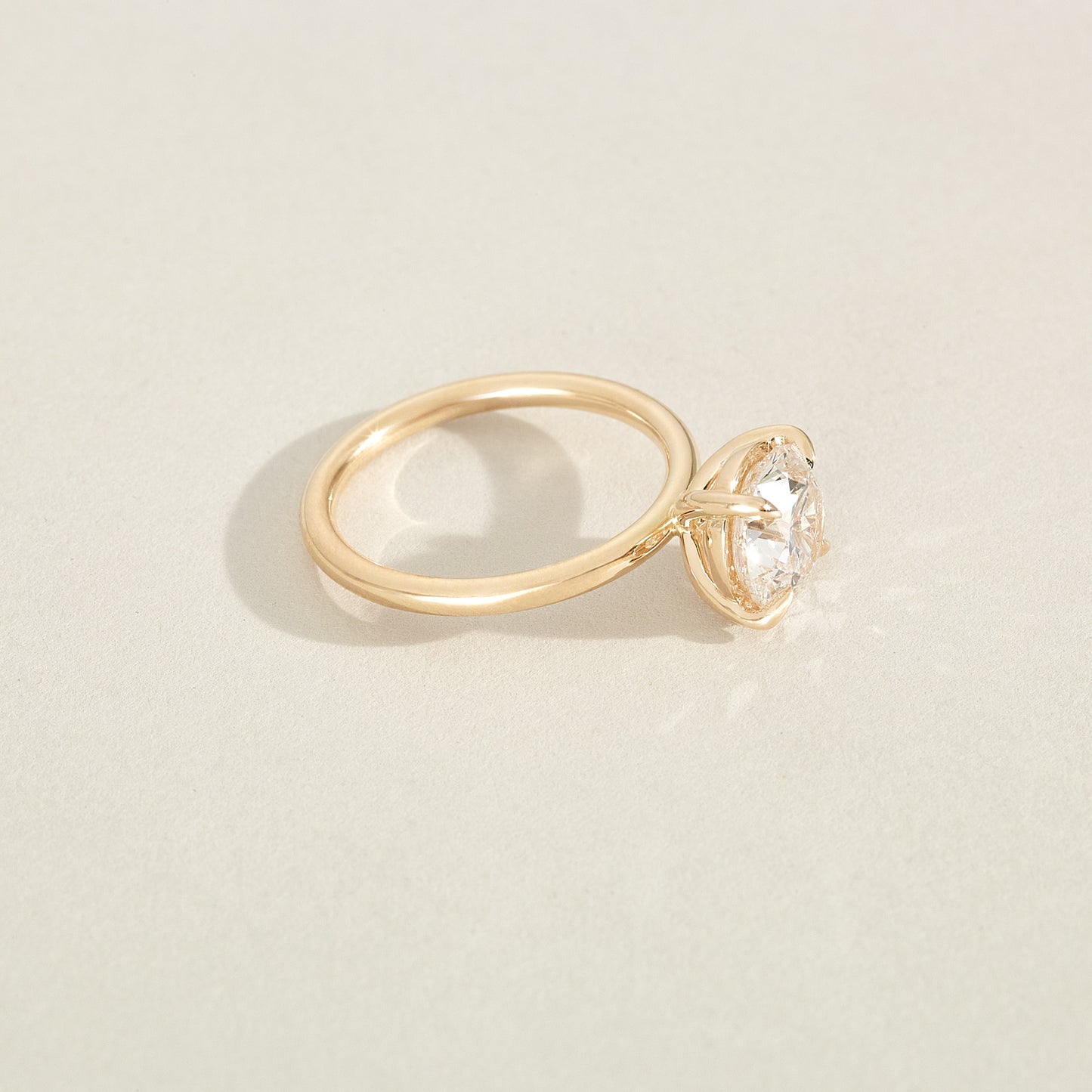 Gold ring with a diamond on a beige background