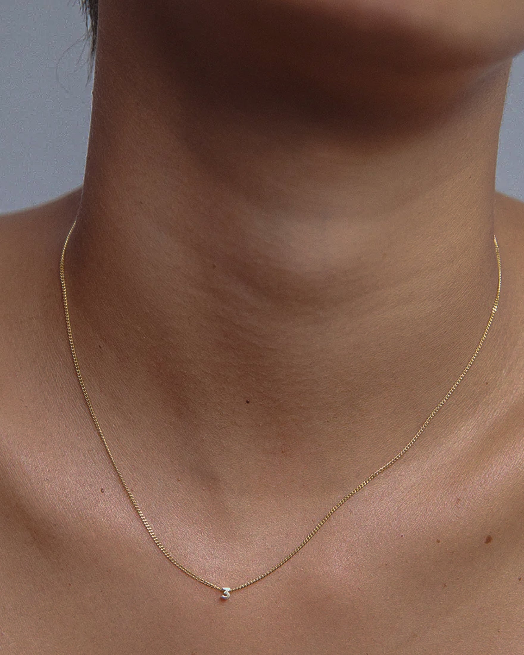 Close-up of a delicate gold chain necklace with a small diamond pendant, elegantly resting on a person's neck. Luxurious and minimalist jewellery.