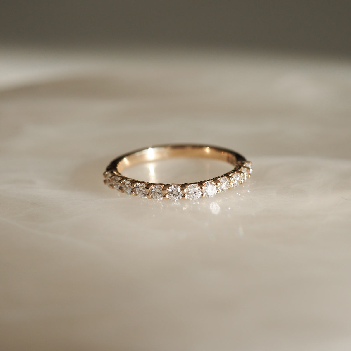 Gold diamond eternity ring on a soft white surface, capturing luxury and elegance. Perfect for special occasions or a timeless accessory.