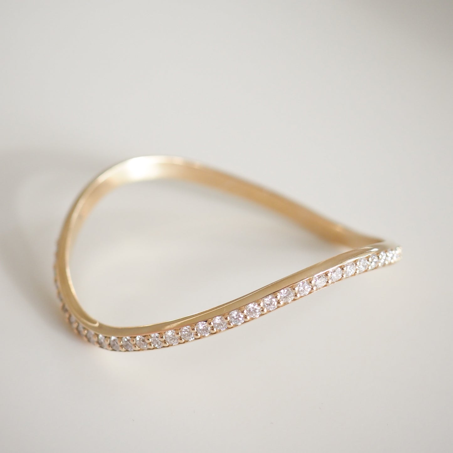 Elegant gold bangle featuring a wavy design adorned with sparkling diamonds, showcasing luxury jewellery craftsmanship.
