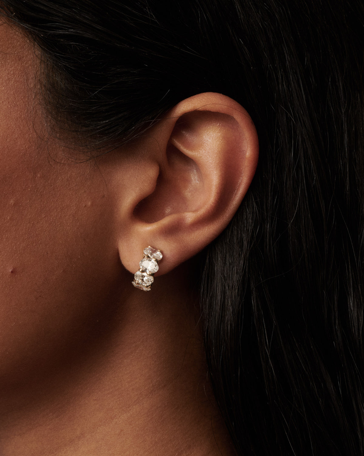 Oval lab-grown diamond hoop earrings in gold, detailed ear close-up