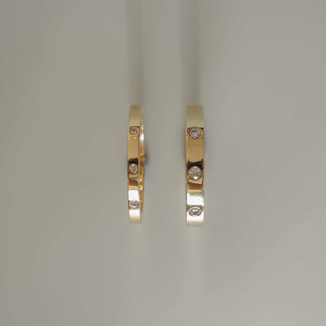 Two gold rings with embedded round diamonds, showcasing luxury jewellery design on a light background.