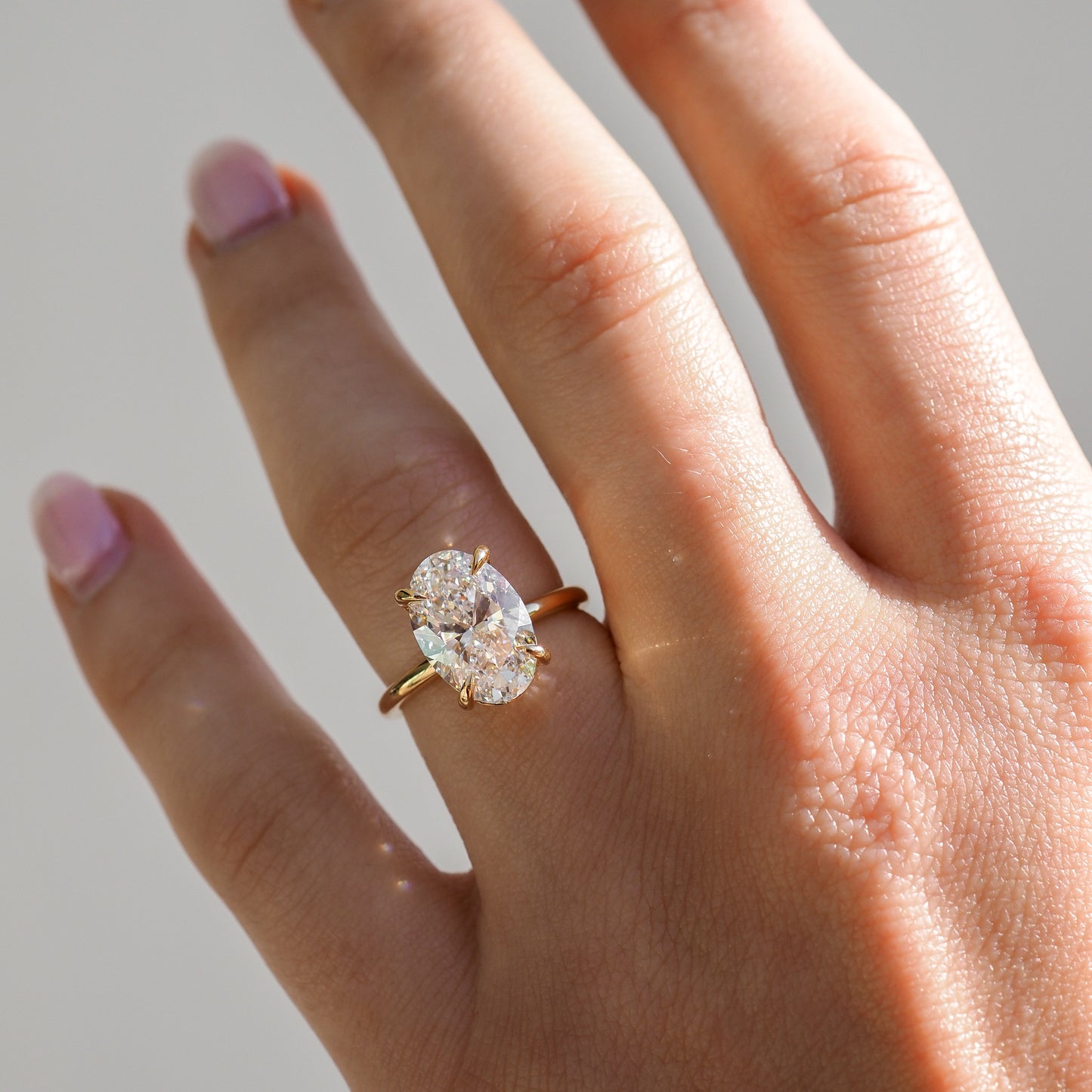 Gold ring with a large, sparkling oval diamond displayed in an open white jewellery box, featuring the brand "Kate & Kole".