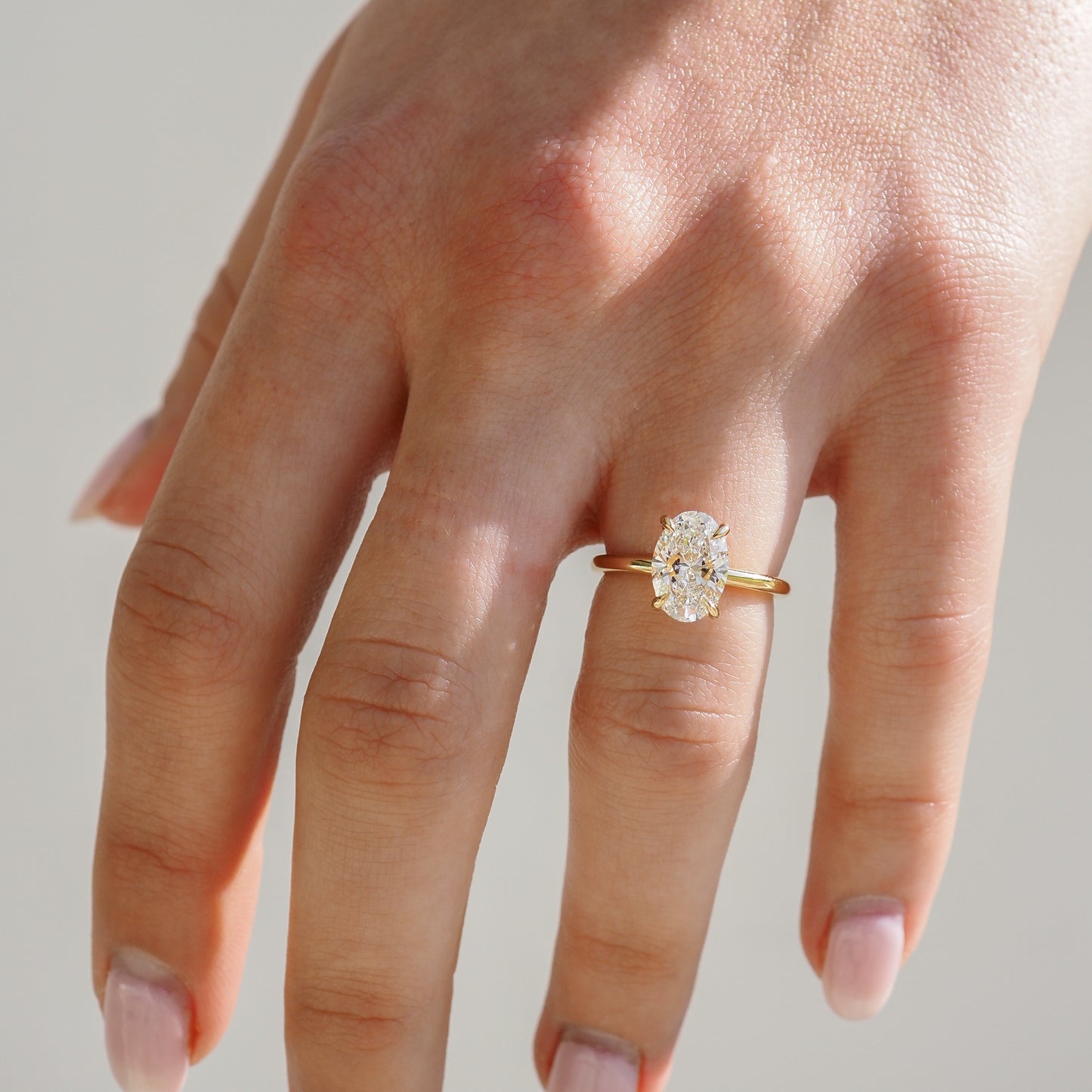 A hand displaying an oval diamond ring with a gold band, capturing a sense of luxury and elegance.