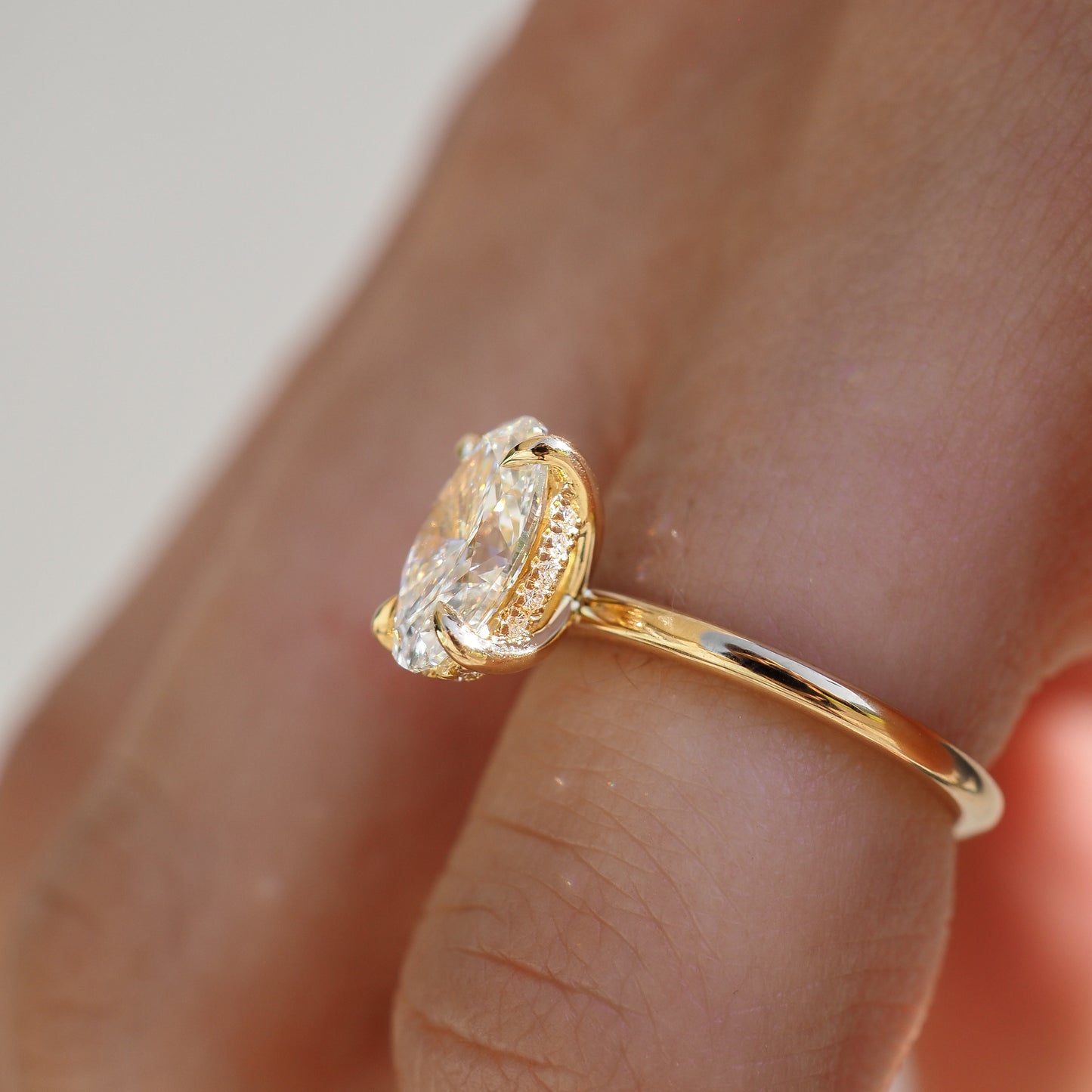 Gold ring featuring an oval diamond on a finger. Luxurious and elegant jewellery design showcasing high-end craftsmanship.