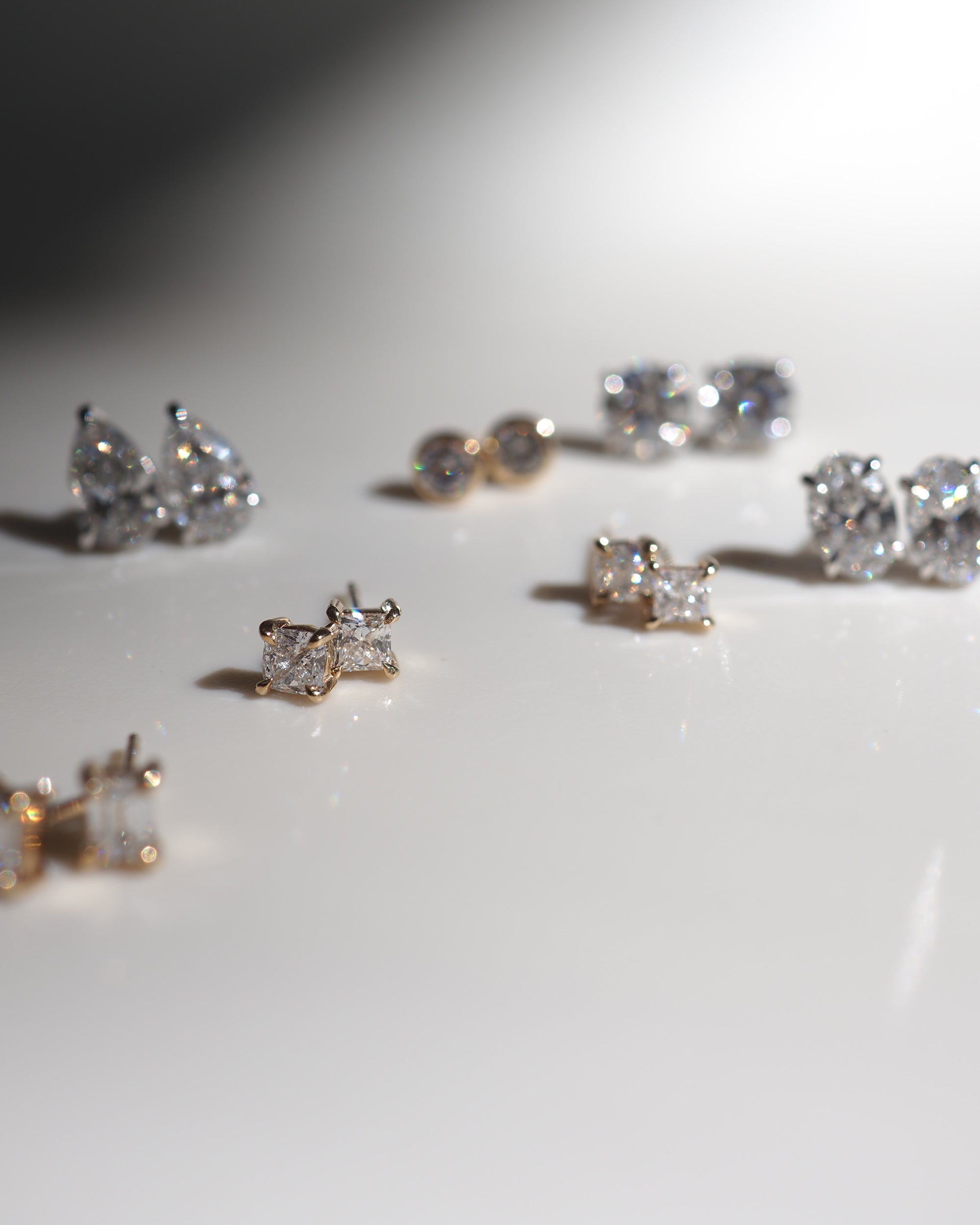 Close-up of elegant diamond stud earrings displayed on a glossy surface, showcasing luxury jewellery design with sparkling brilliance.
