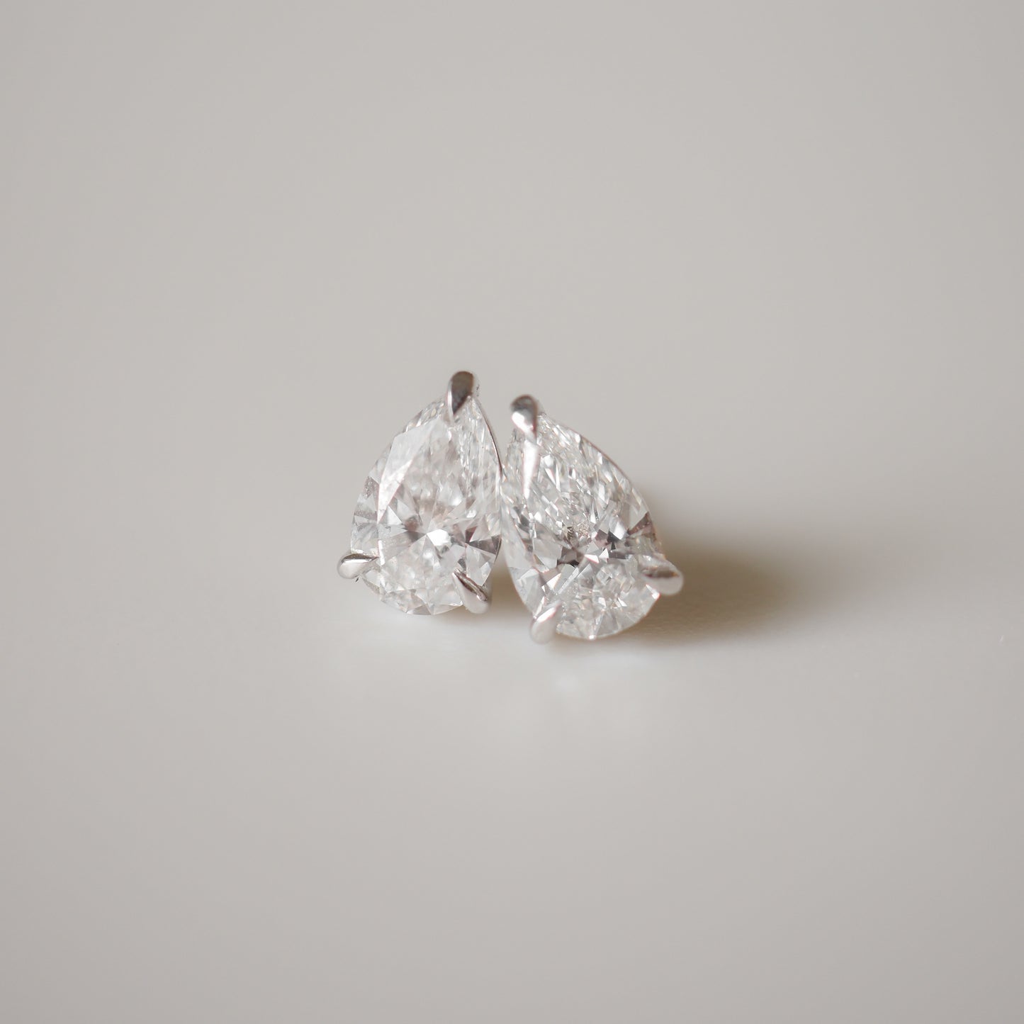 Pear-shaped diamond earrings on a plain surface, showcasing luxury and elegance in fine jewellery design.