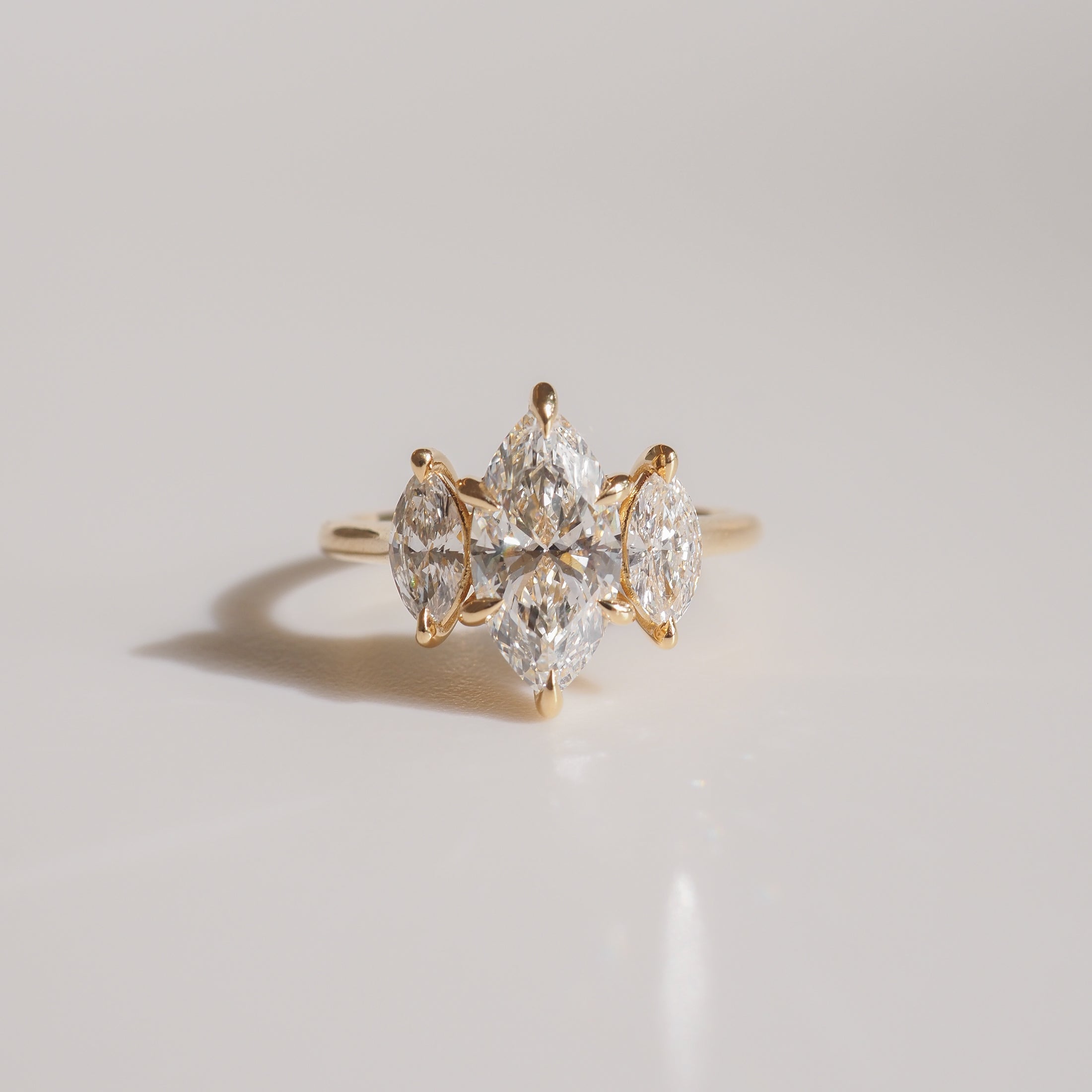 Gold ring featuring a central marquise-cut diamond surrounded by four smaller marquise diamonds, elegantly displayed on a light background.