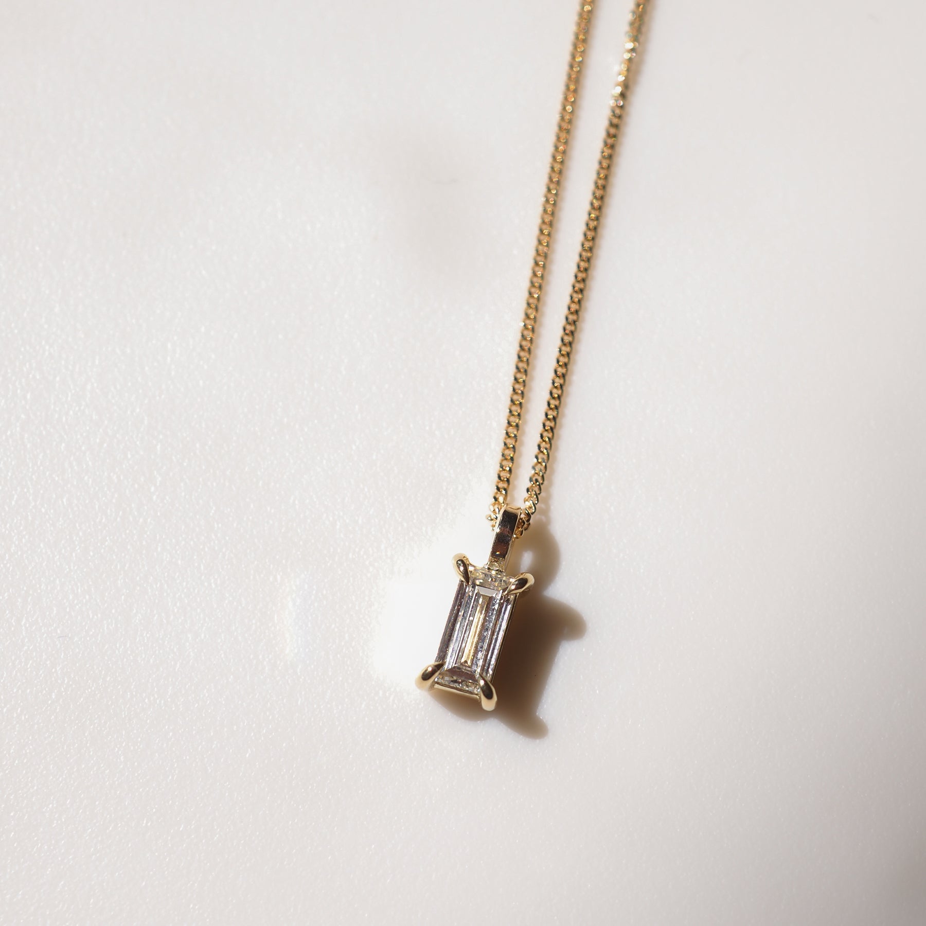 Gold chain necklace featuring a radiant, rectangular gemstone pendant. Subtle elegance in high-end jewellery design.