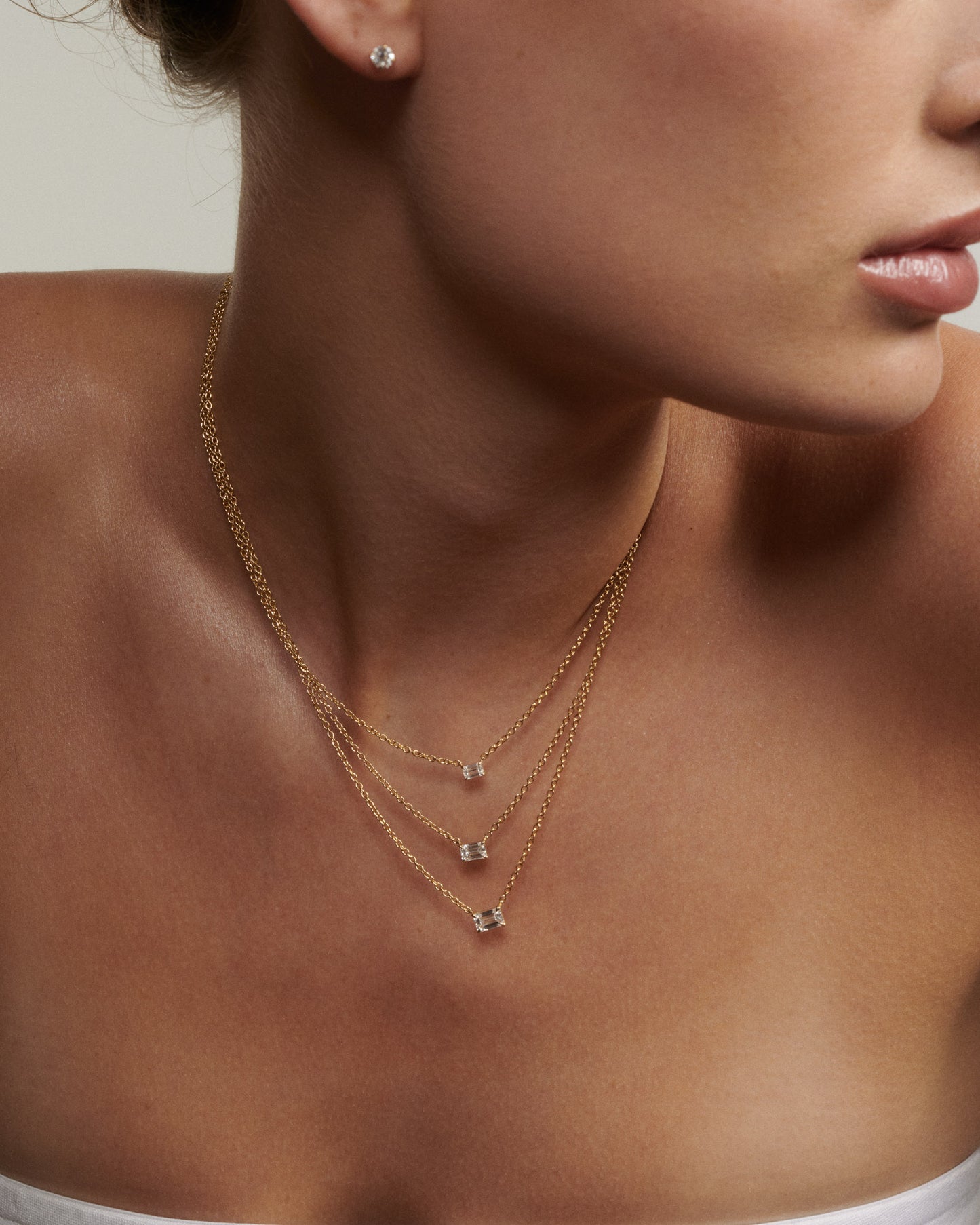 Close-up of a woman wearing a gold necklace with small pendants.