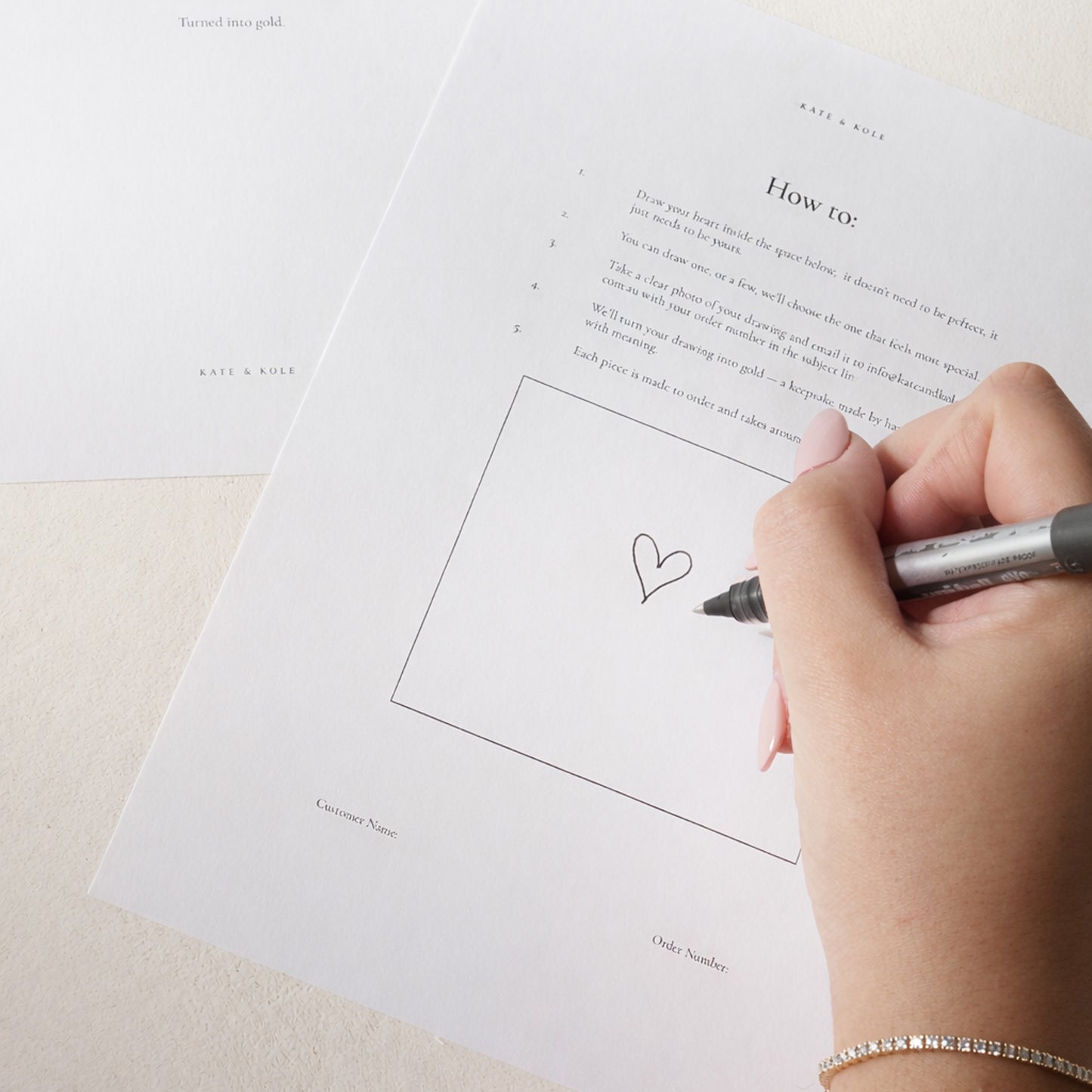 Hand drawing a heart on a piece of paper with a pen.