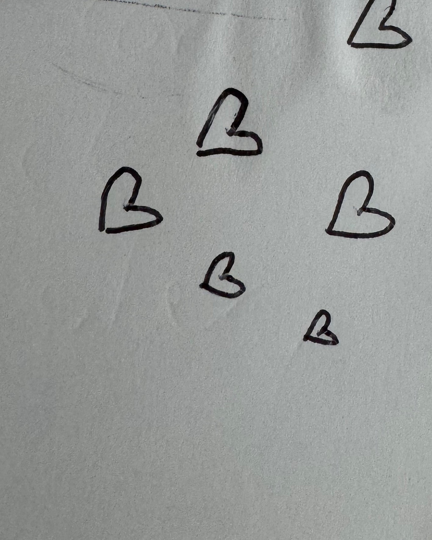 Hand-drawn black hearts scattered on a light grey paper background, evoking elegant jewellery design inspiration.