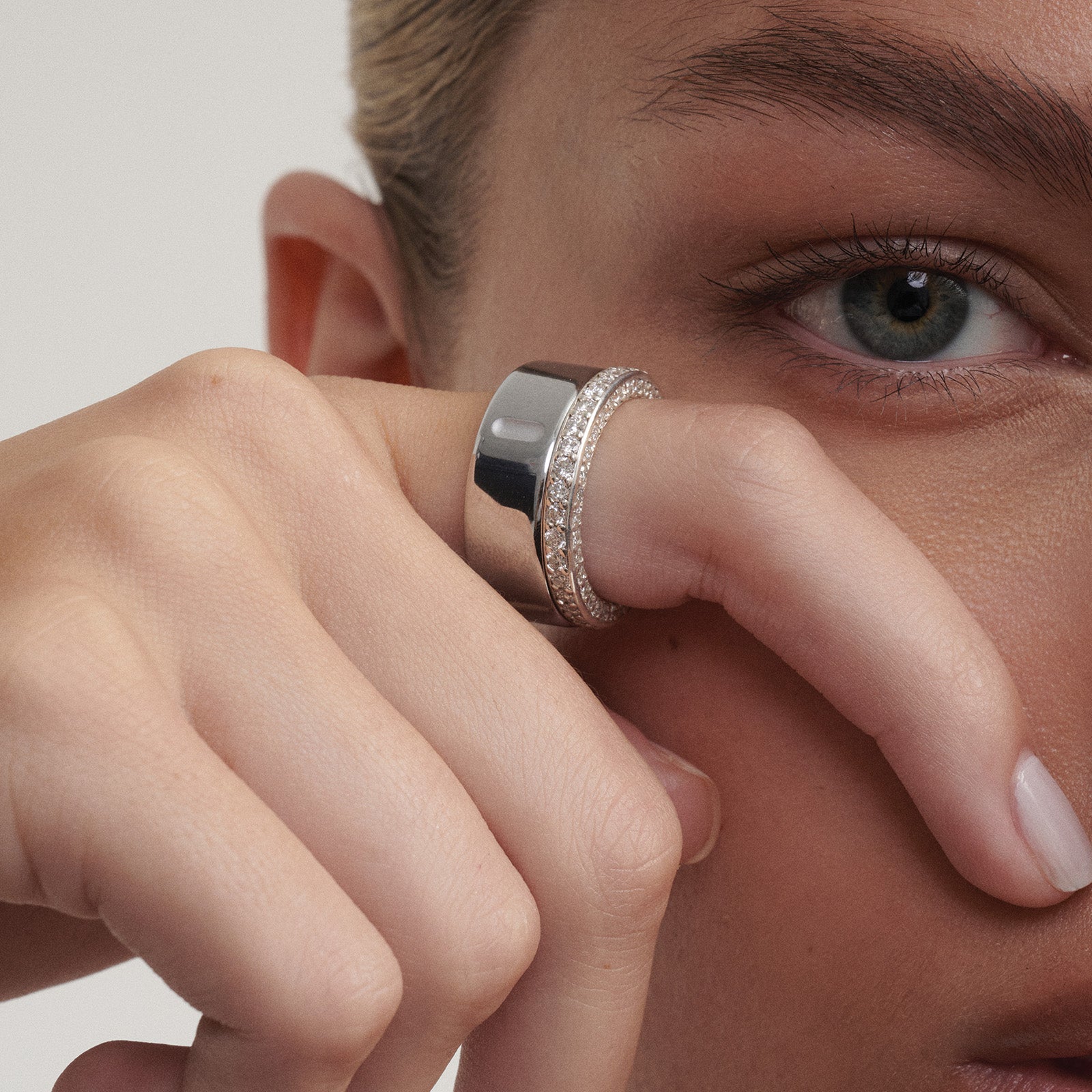 Close-up of a person wearing a white gold  ring on their finger alongside their Oura Ring