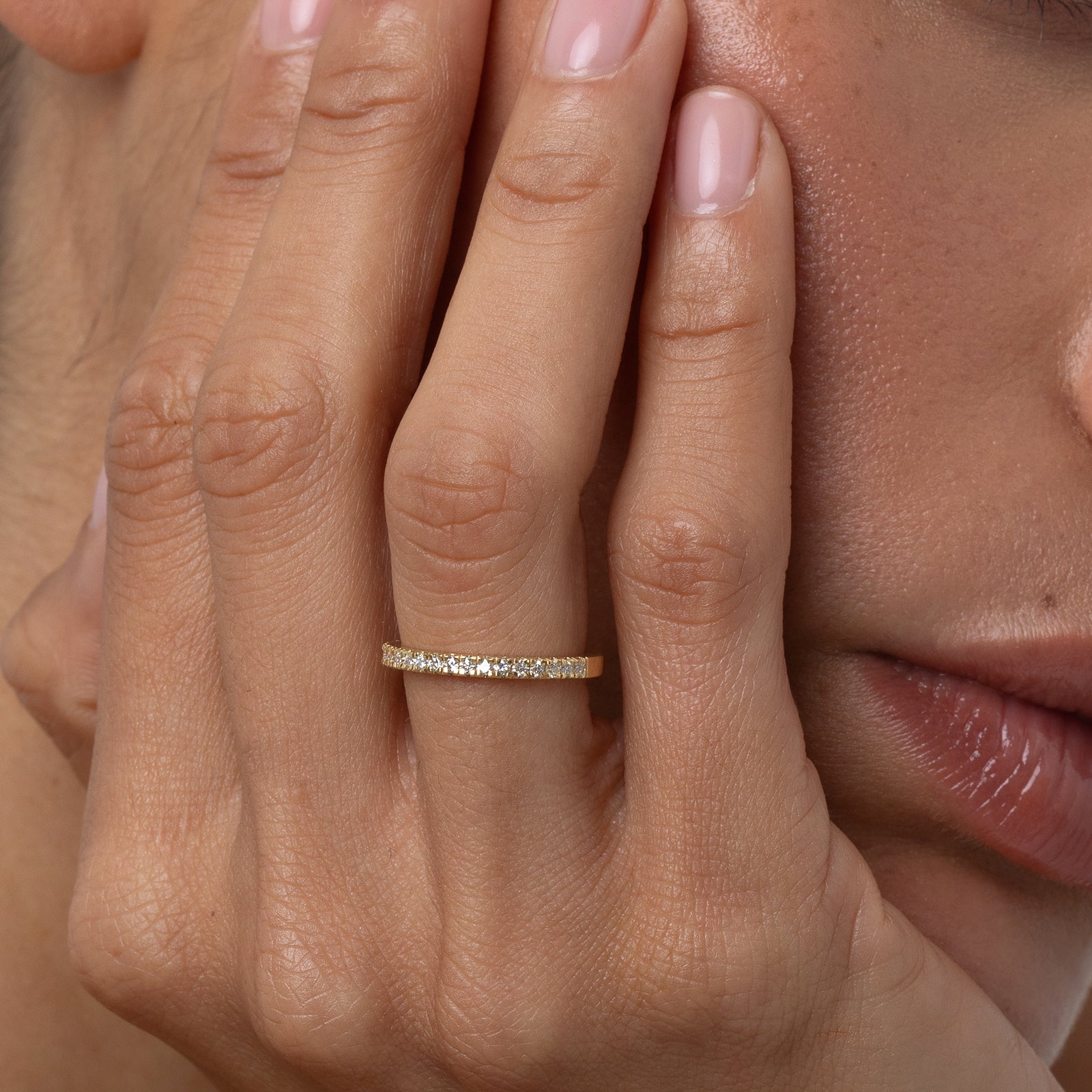 Close-up of a hand wearing a gold ring with a blurred background