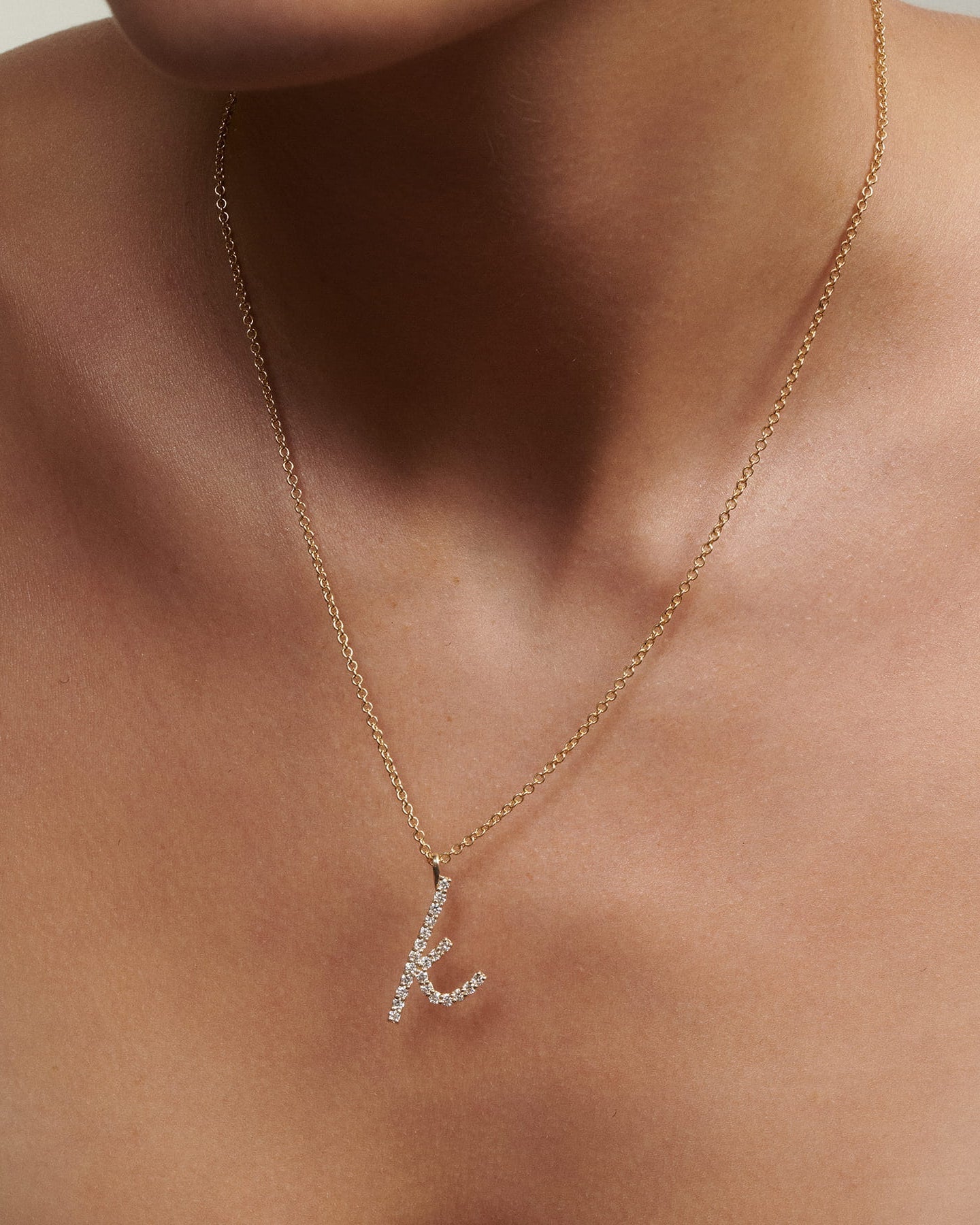 Close up of woman wearing Script Diamond Letter Necklace in gold