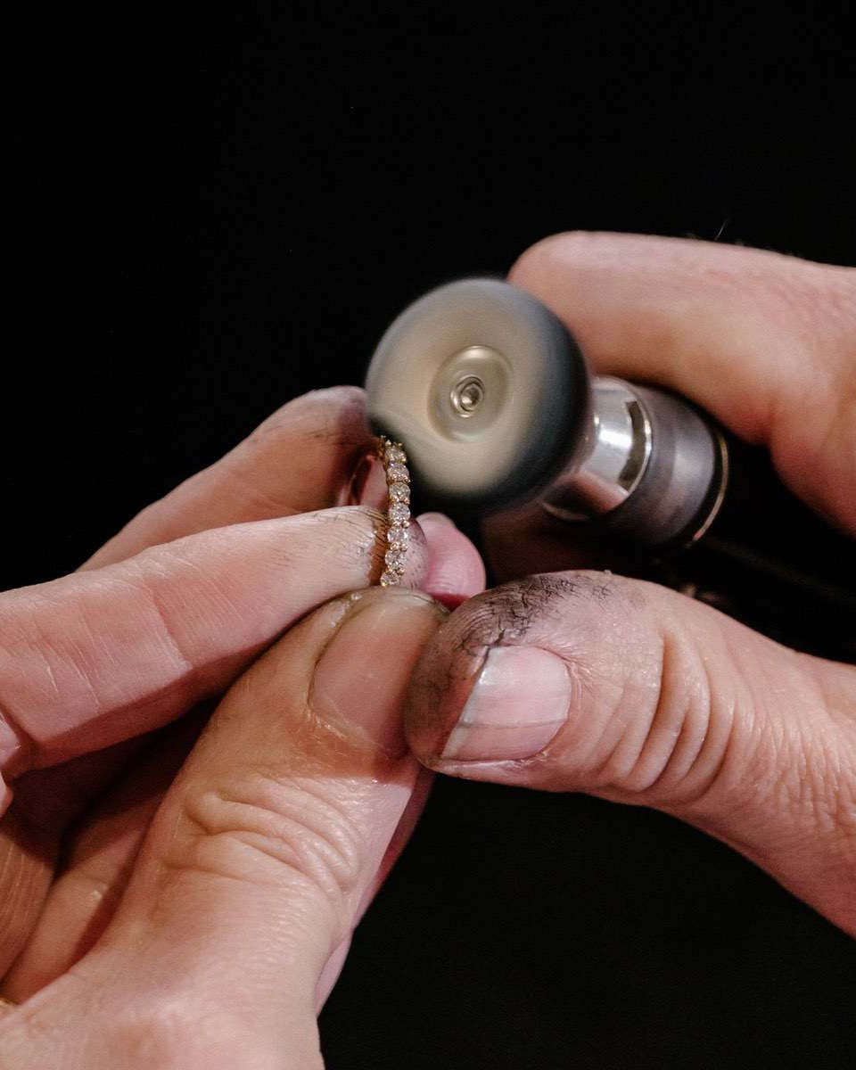 Arraya diamond wedding band being made with our in studio jewellers. Image of our jeweller polishing the 18ct yellow gold band