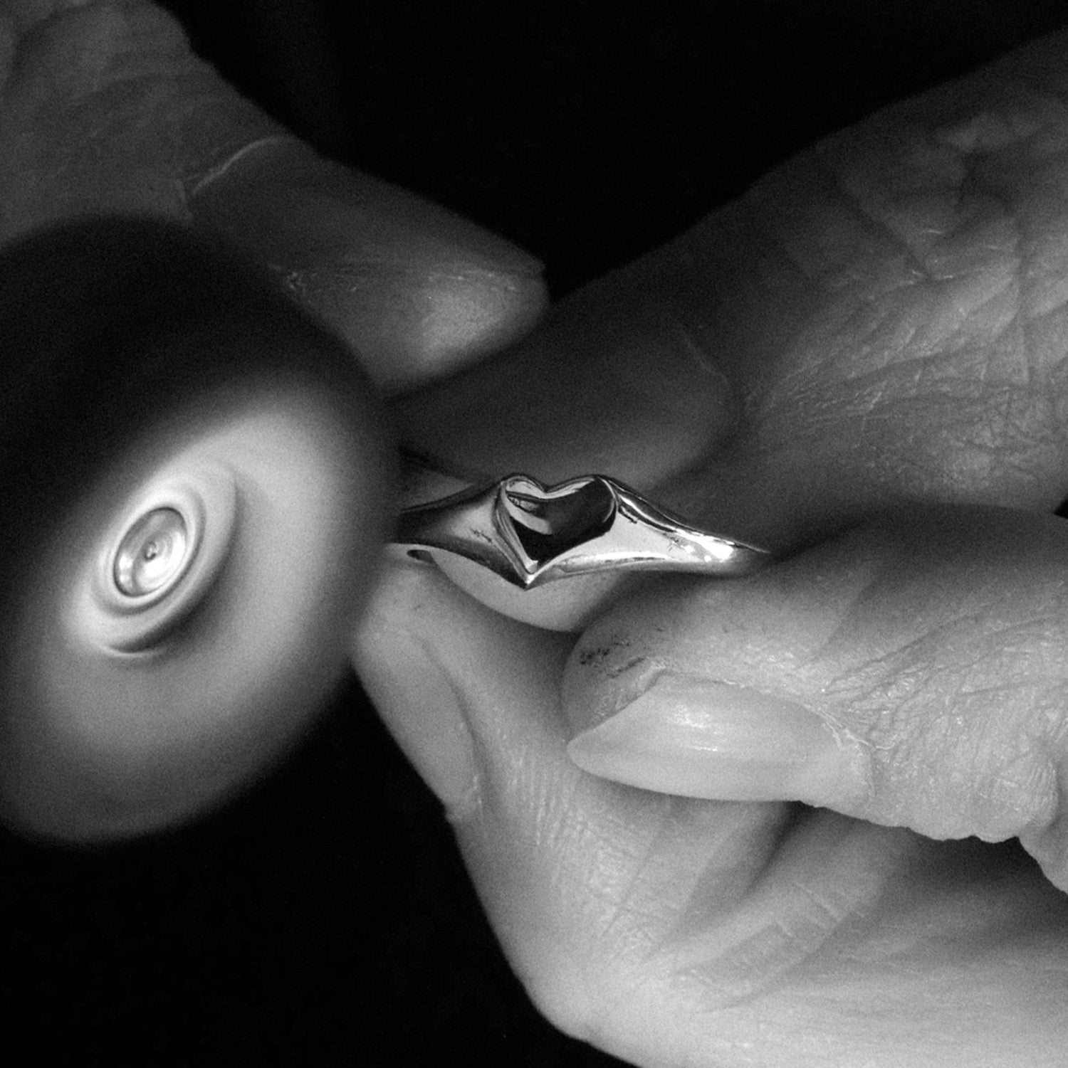 Close-up of a hand holding a small metal object with a wheel-like component.