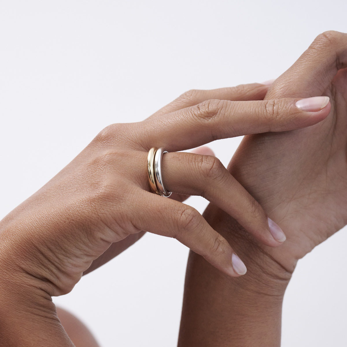 Elegant close-up of hands wearing a luxury dual-tone gold and silver ring. Minimalist jewellery, high-end style.