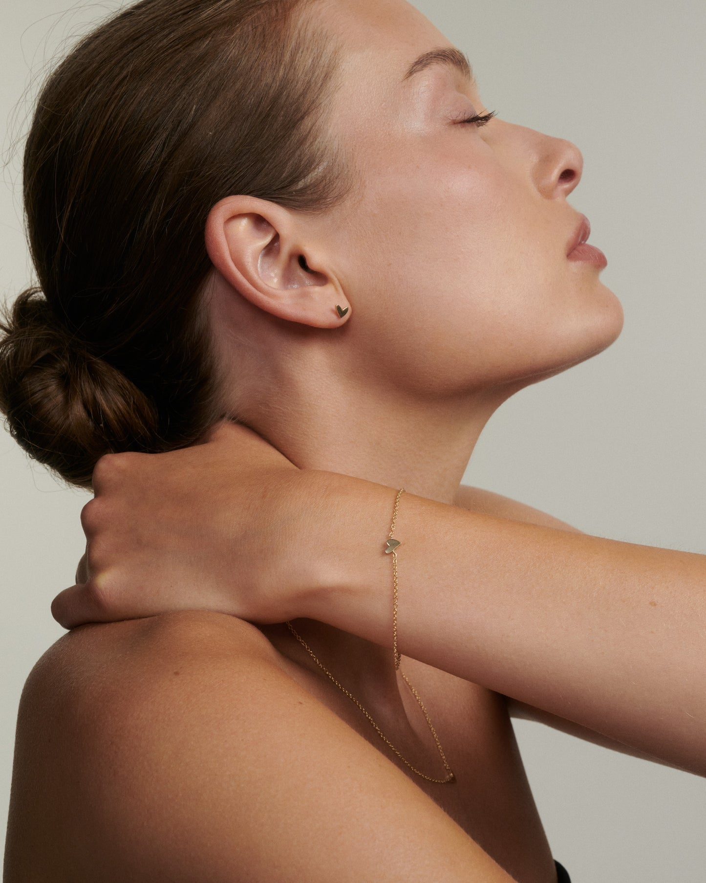 Woman wearing a delicate gold necklace against a neutral background