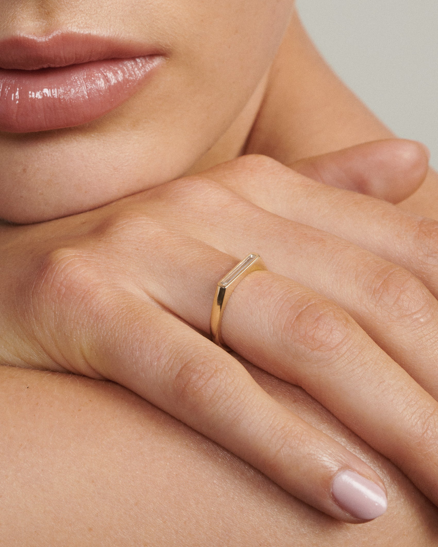 Close-up of a hand wearing a gold ring with a blurred background