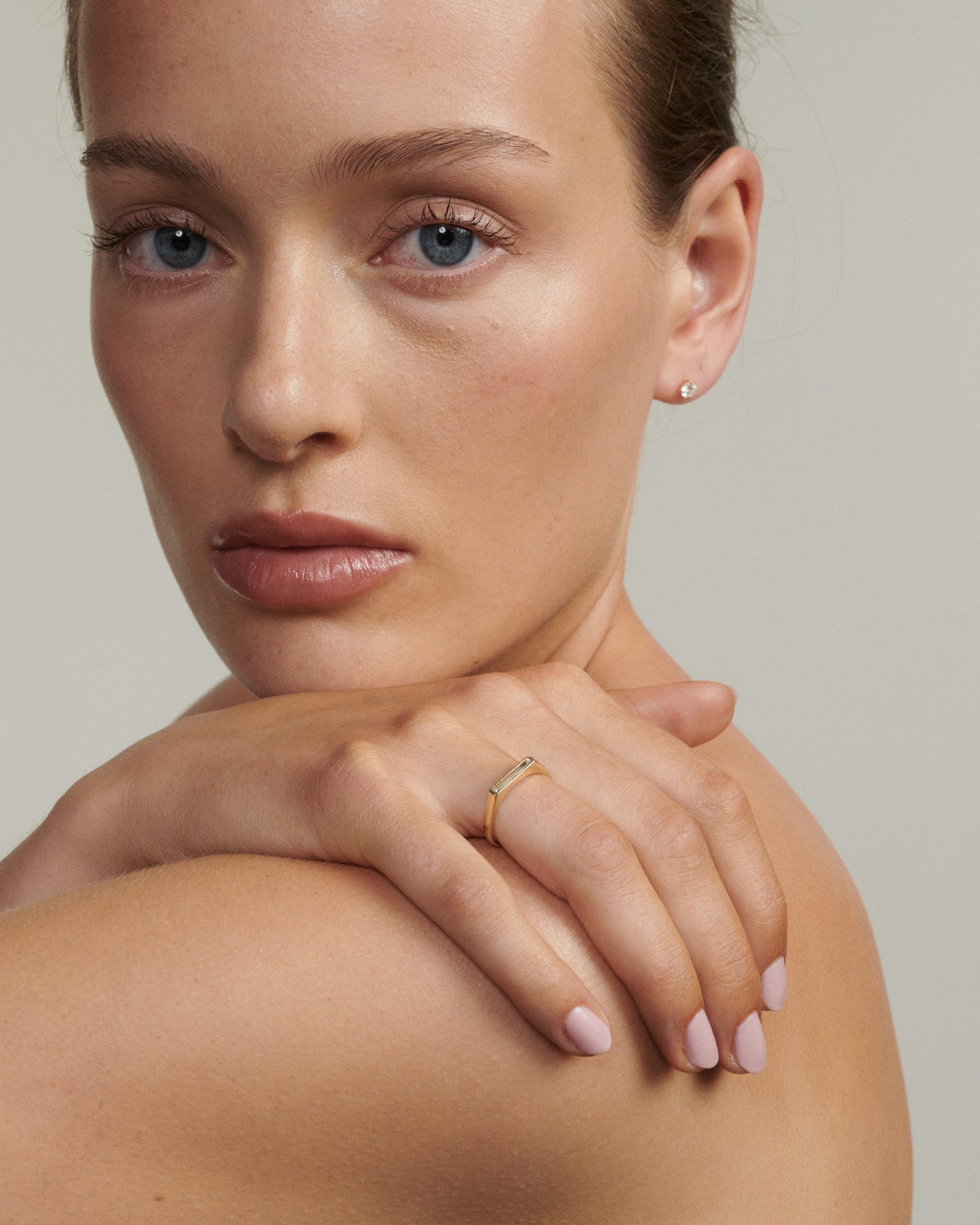 Close-up of a woman's hand with a ring on a neutral background