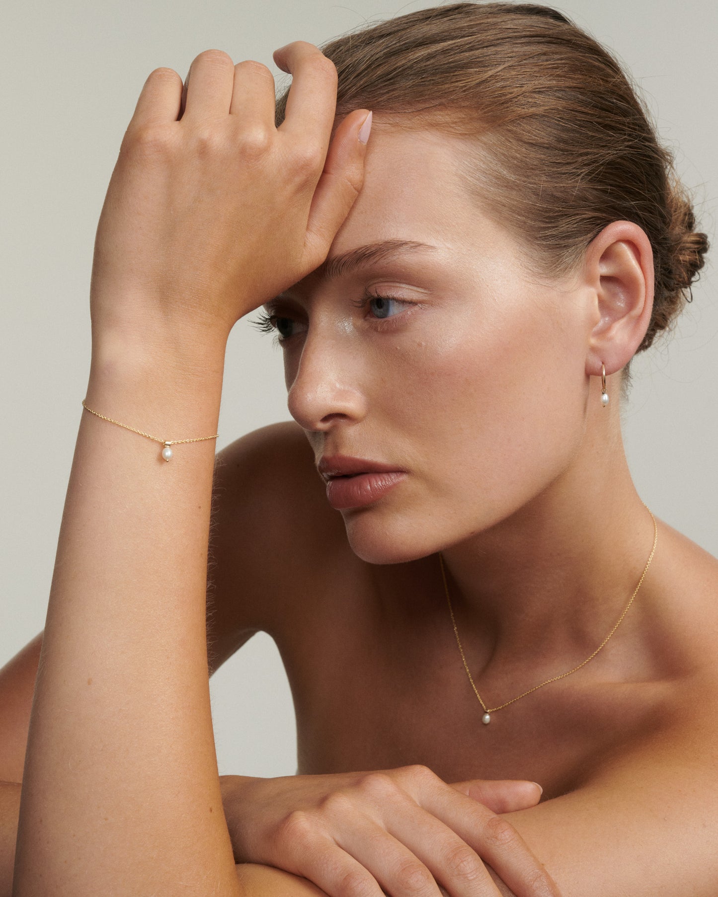 Woman wearing gold jewelry with a plain background