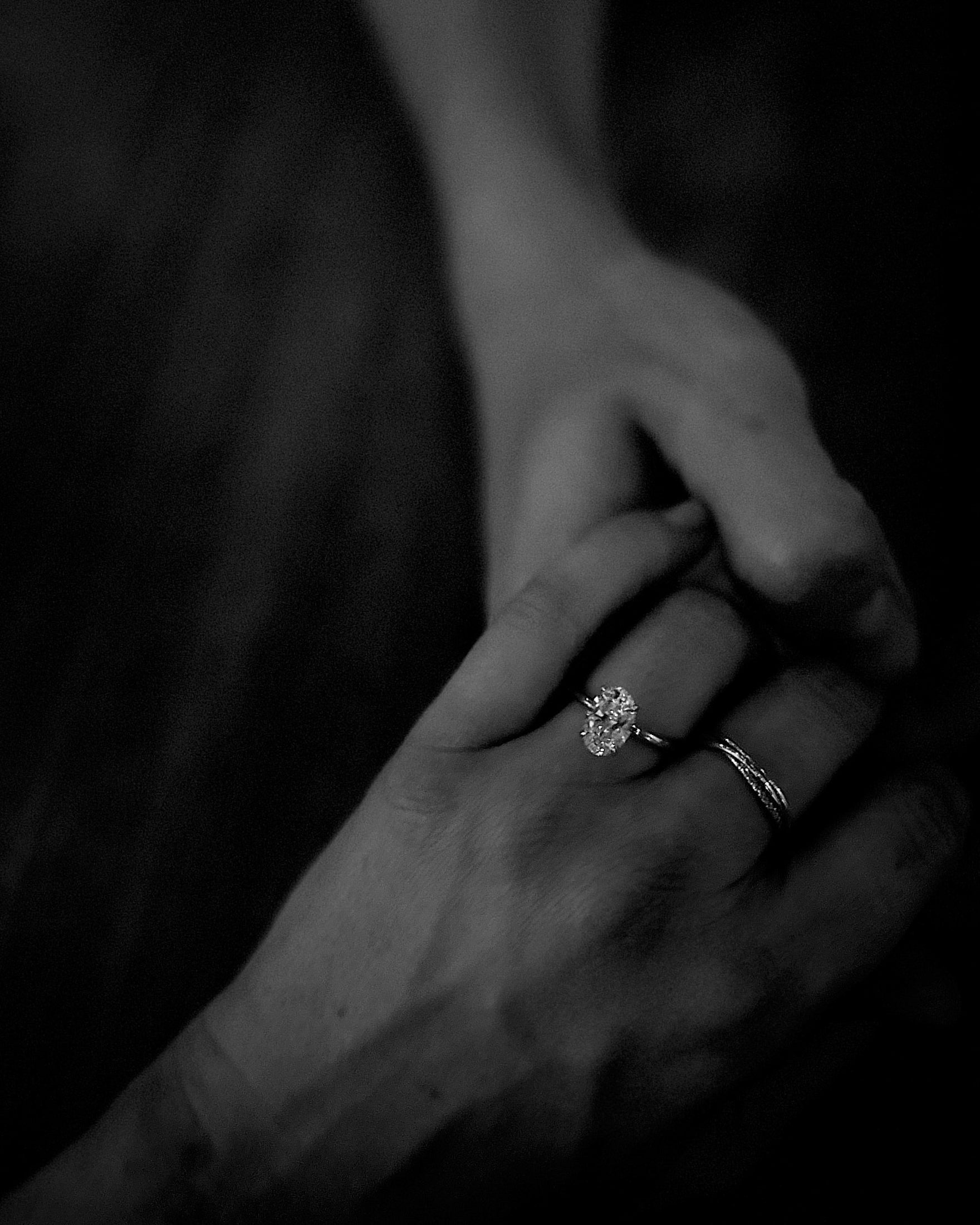 Two hands holding, featuring a sparkling diamond engagement ring, symbolising love and luxury. Dark, elegant atmosphere.