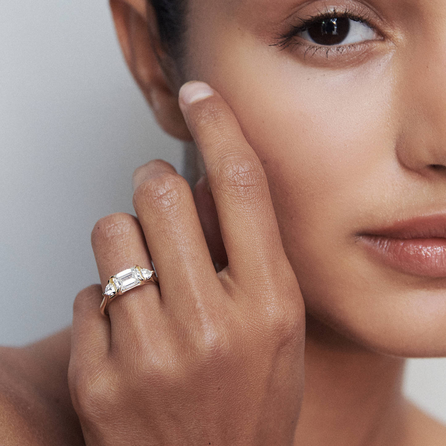 Woman's hand elegantly displaying a baguette-cut diamond ring. Luxurious jewellery piece on a warm skin tone, softly focused background.