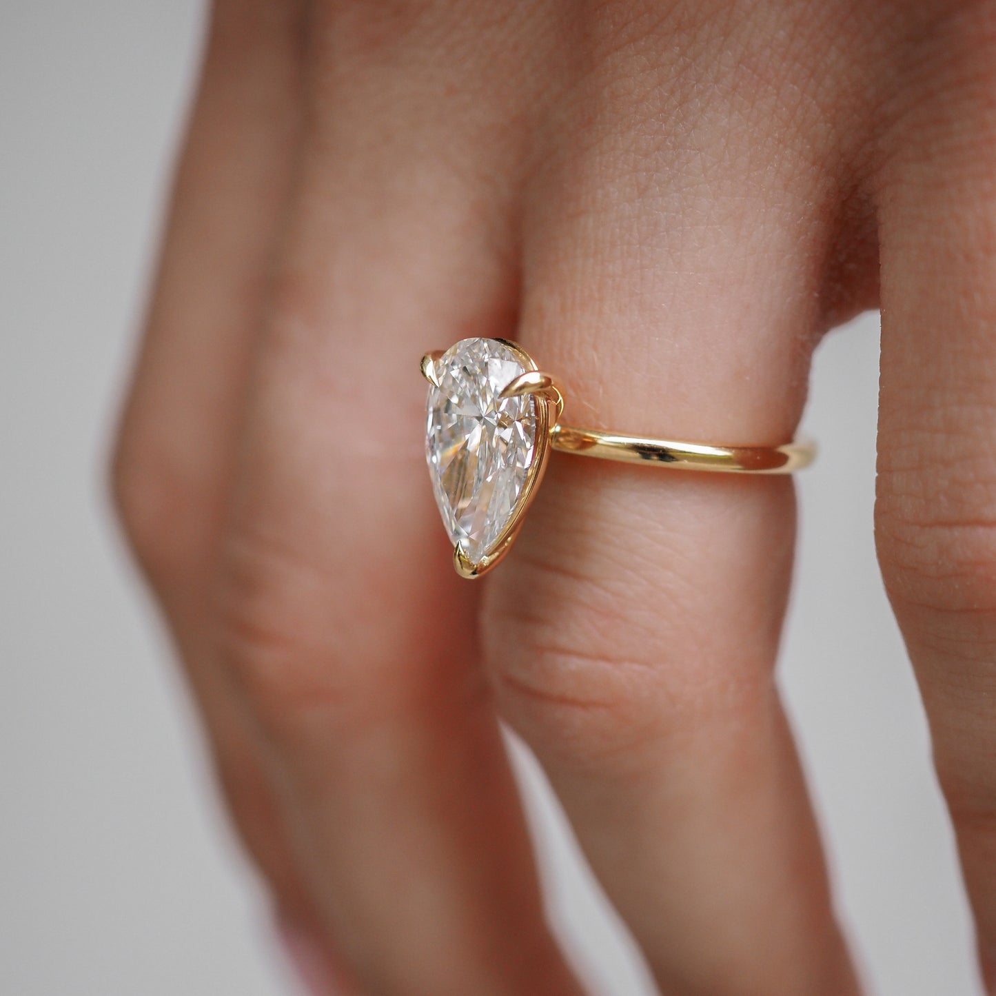 Gold ring with a pear-shaped diamond, elegantly worn on a hand. High-end jewellery showcasing luxury design and craftsmanship.