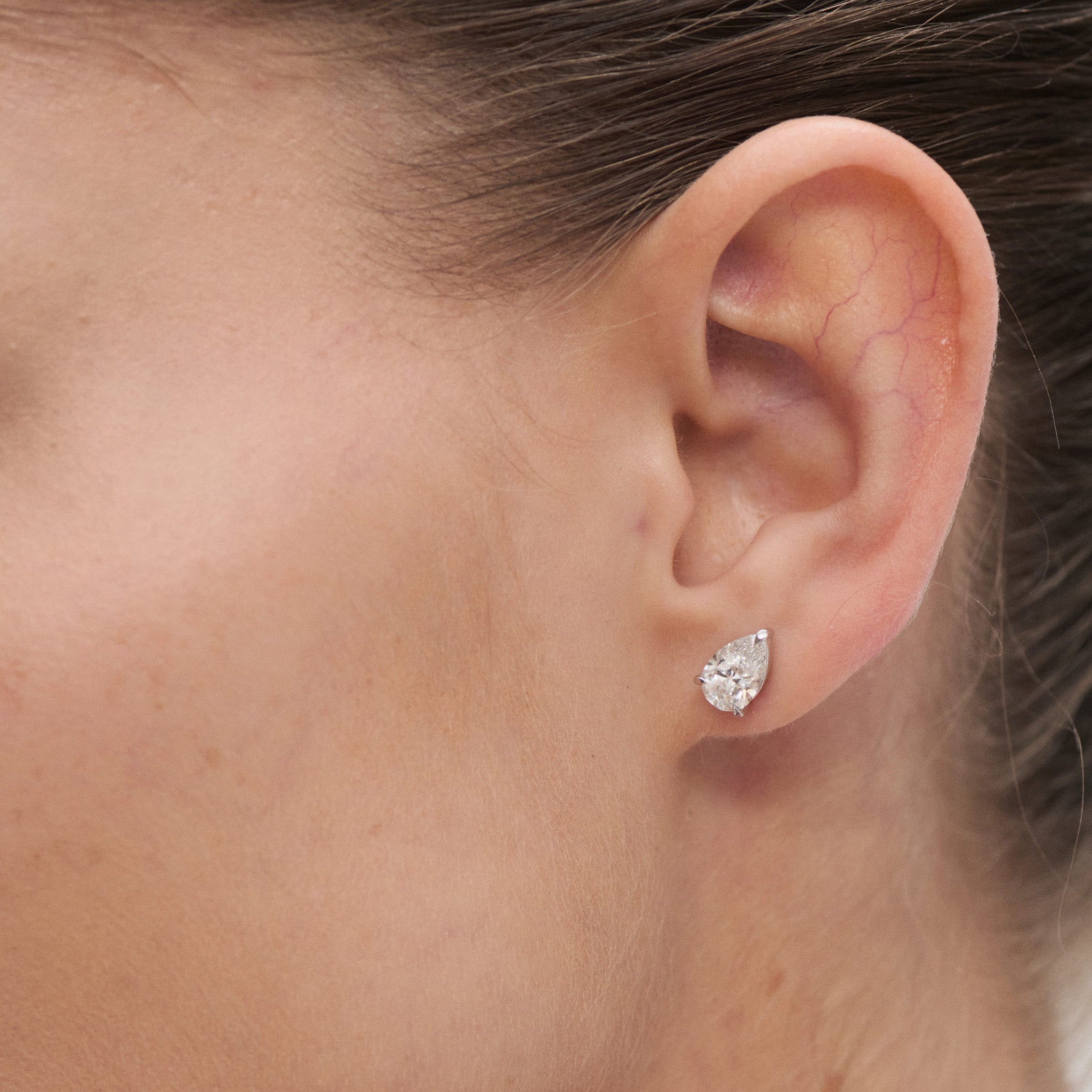 Close-up of a model wearing a pear diamond earring 