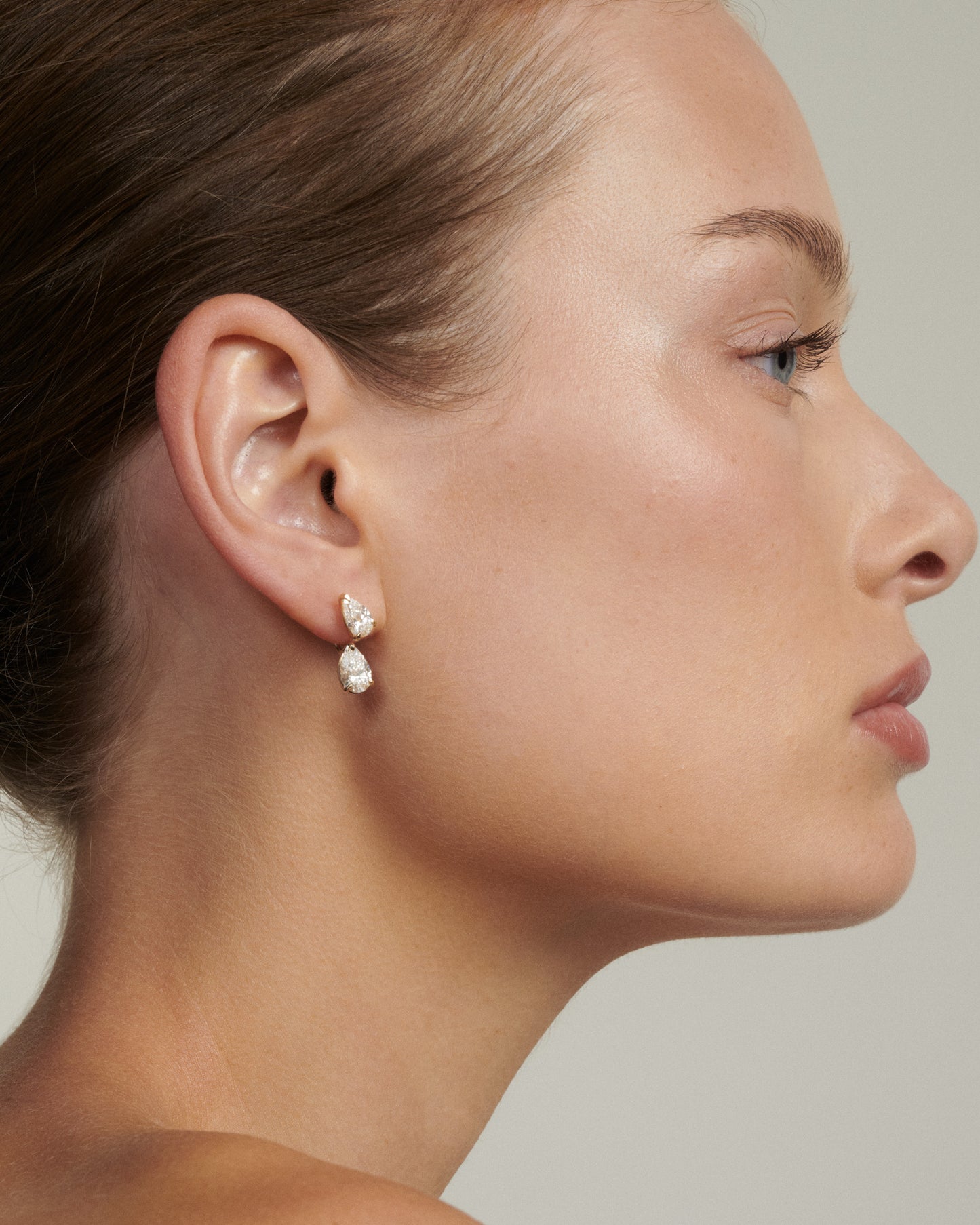 Close-up of a woman wearing a pair of earrings with a neutral background