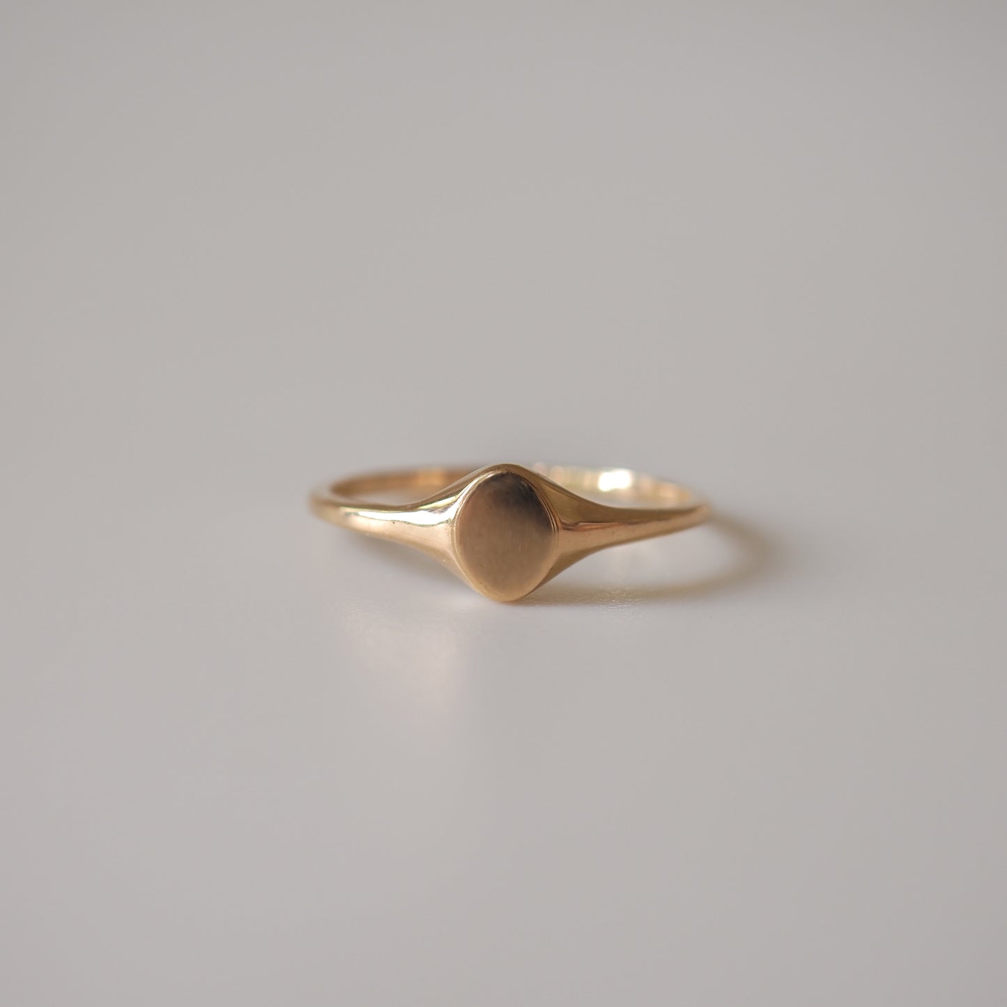 Elegant gold signet ring on a smooth surface, minimalistic design, luxury jewellery.