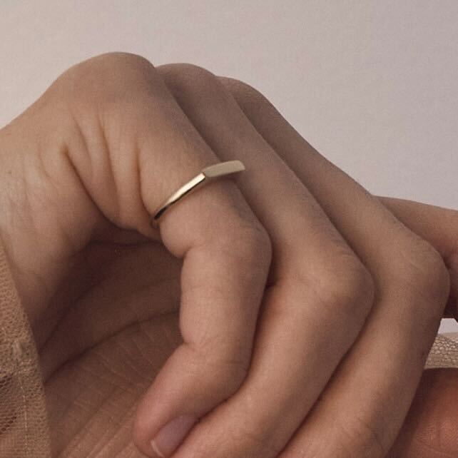 Gold ring on a person's finger against a neutral background