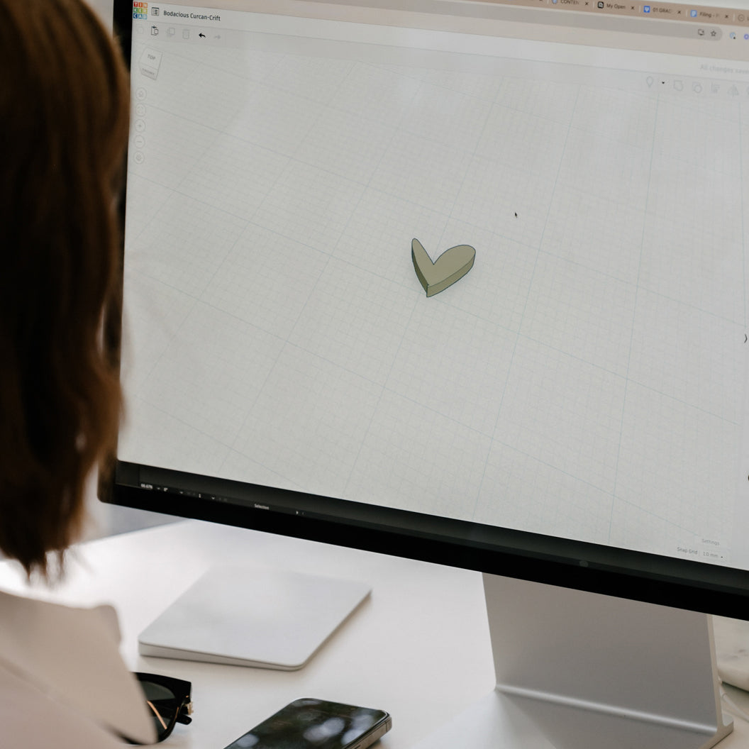 A person designs a heart-shaped jewellery piece on a computer using CAD software, highlighting innovative luxury jewellery design technology.