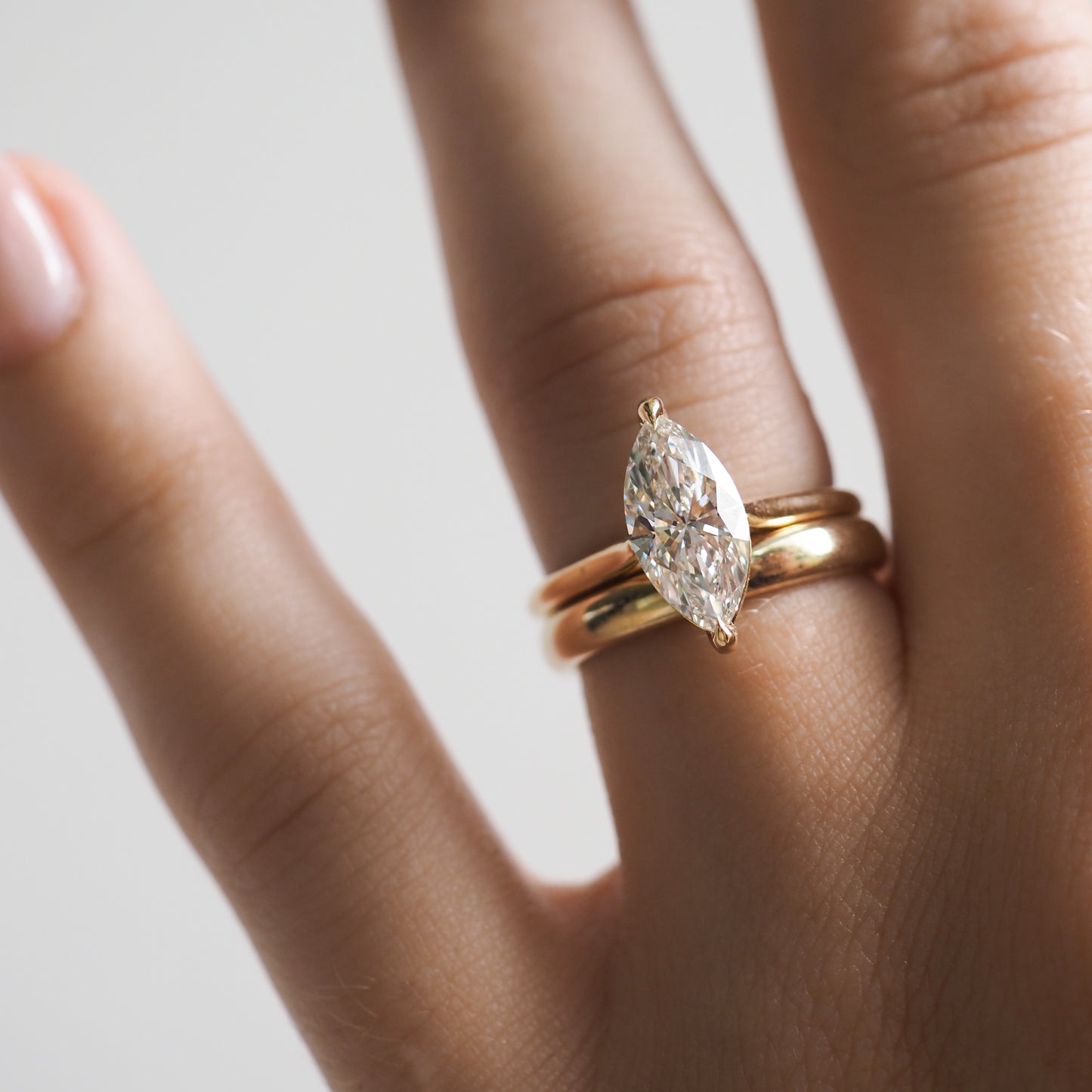 Hand wearing a marquise-cut diamond solitaire ring with a gold band, embodying luxury jewellery craftsmanship.
