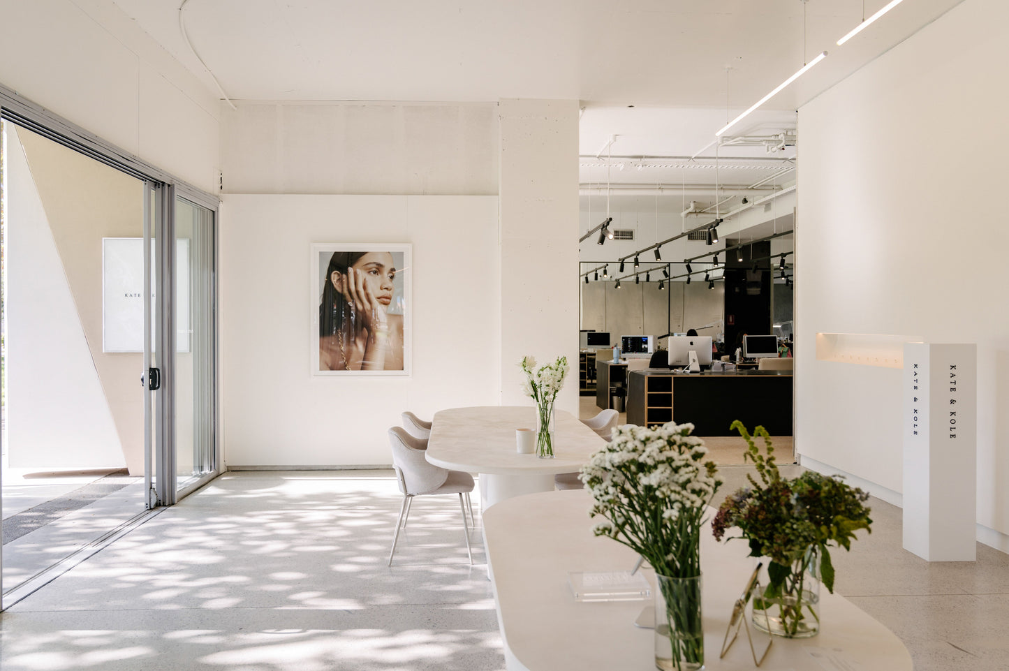 Bright and airy luxury jewellery store interior with elegant decor, large artwork, modern furniture, and fresh flowers enhancing the sophisticated ambiance.
