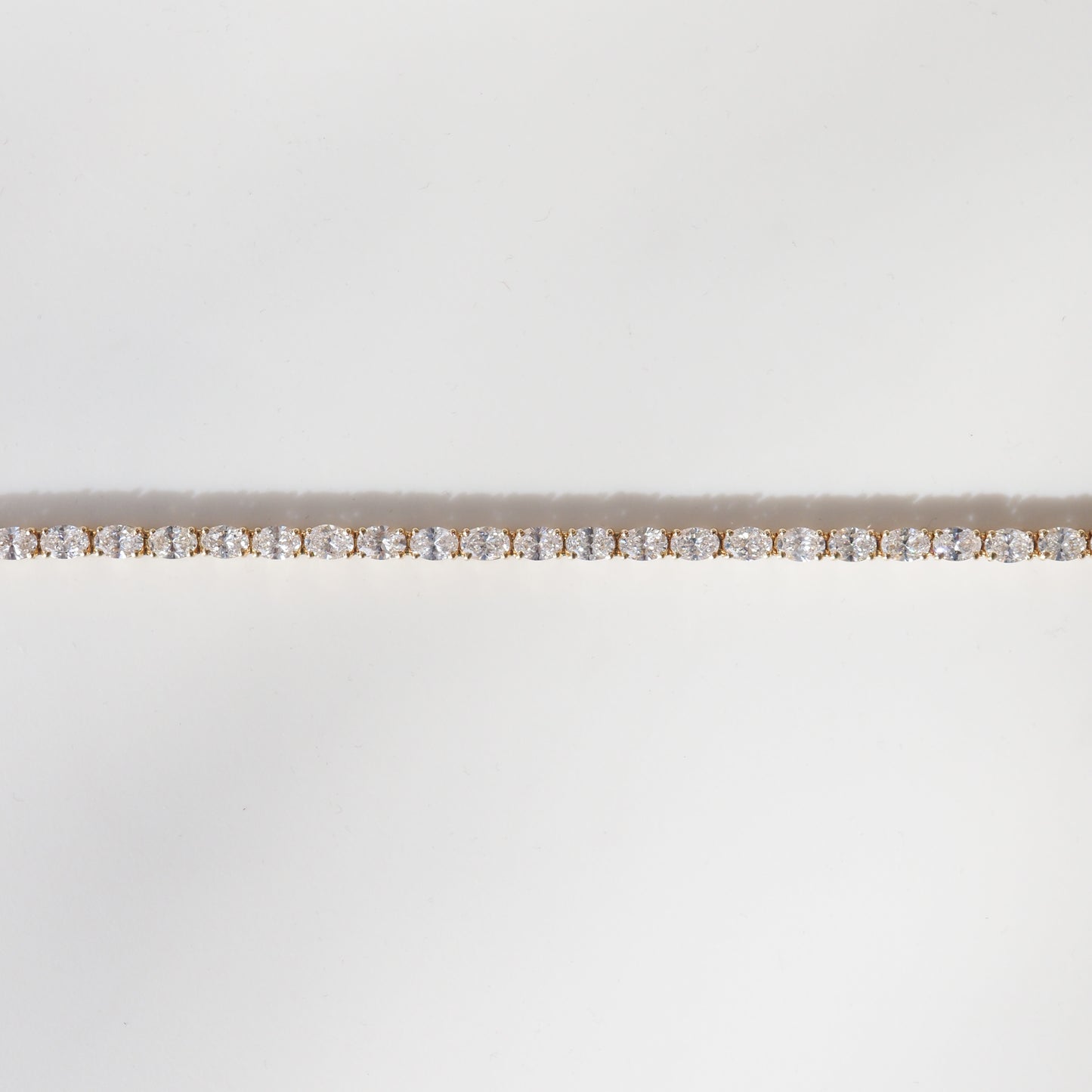 Elegant gold tennis bracelet adorned with sparkling round-cut diamonds, set against a plain white background.