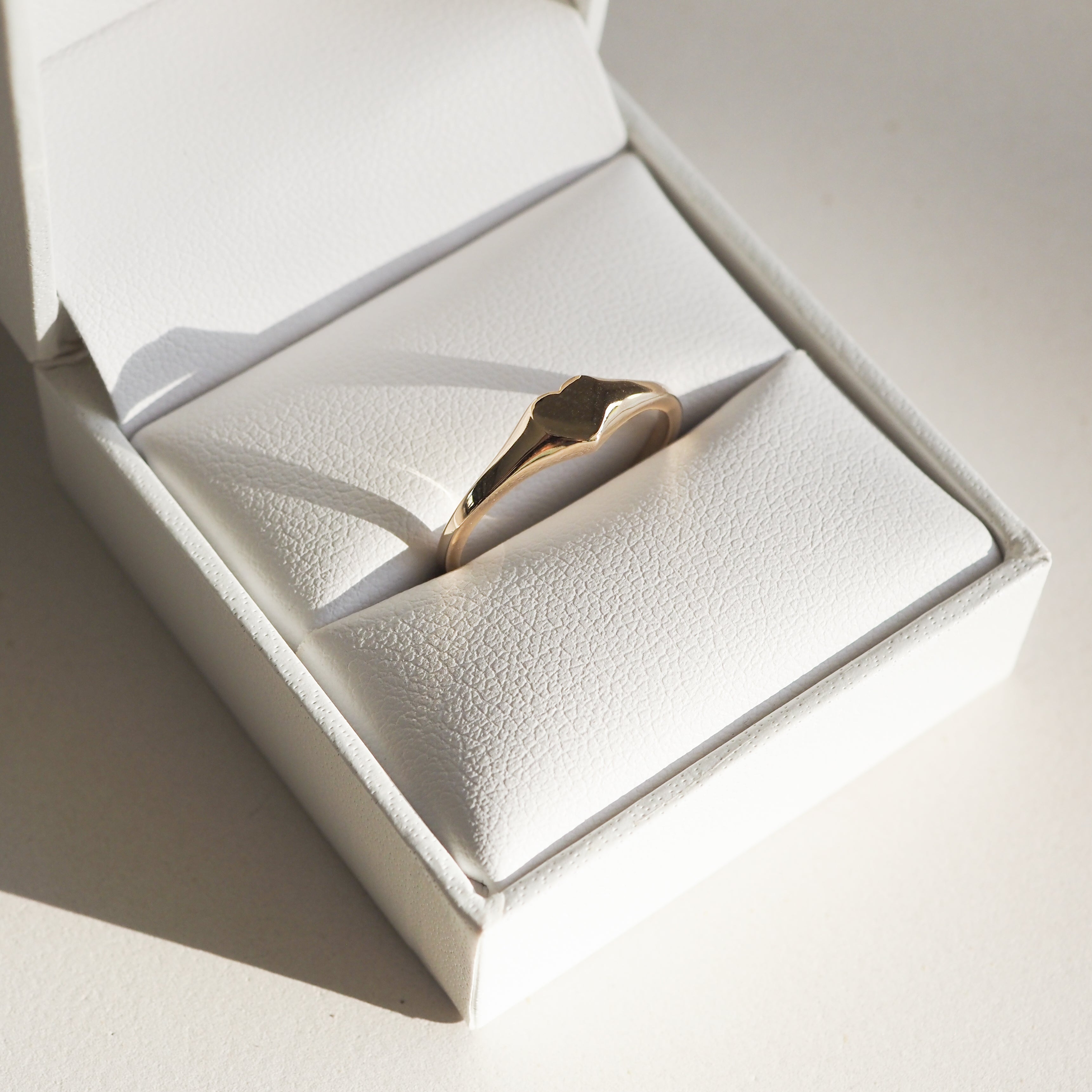 Gold ring with a sleek, minimalist star design in a white jewellery box, highlighting luxury and elegance.