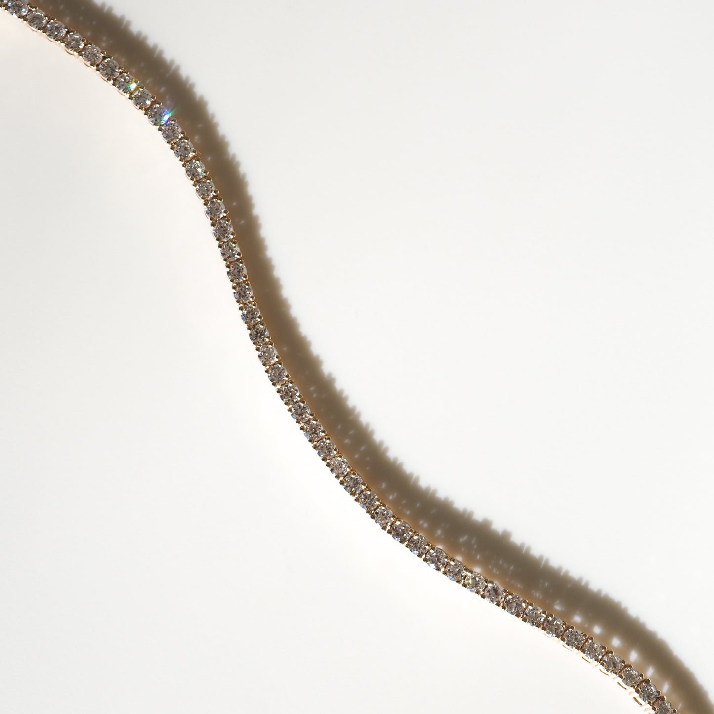 Elegant diamond tennis bracelet on a light background, showcasing sparkling stones and a luxurious gold setting. Perfect for luxury jewellery highlights.