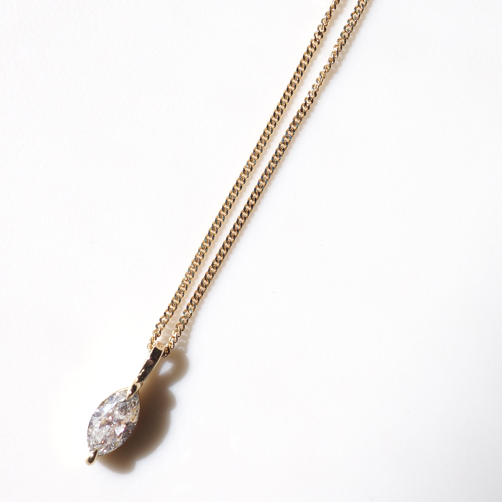 Elegant gold chain necklace featuring a marquise-cut diamond pendant on a white background, showcasing luxury jewellery.
