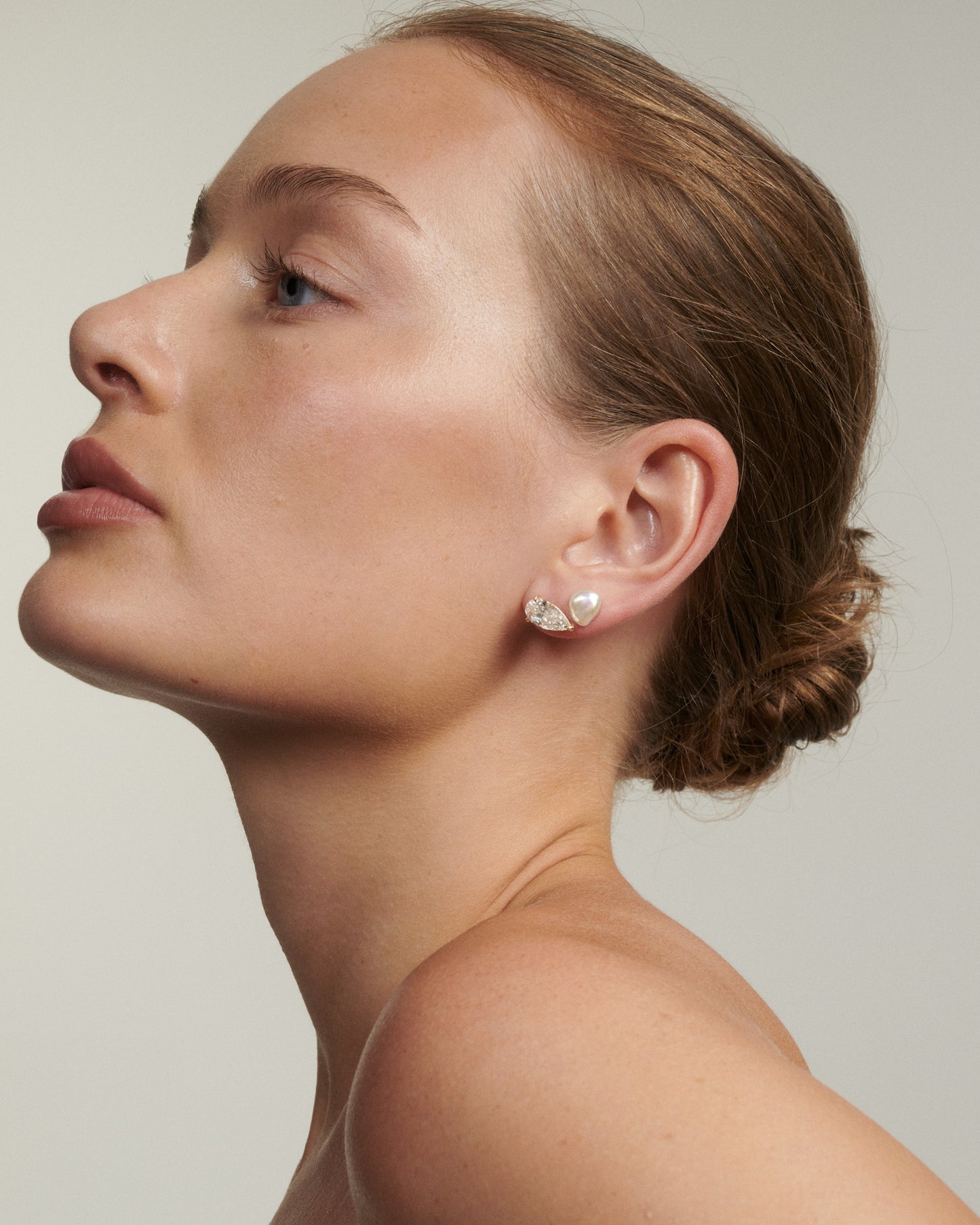 Woman wearing a diamond earring against a neutral background