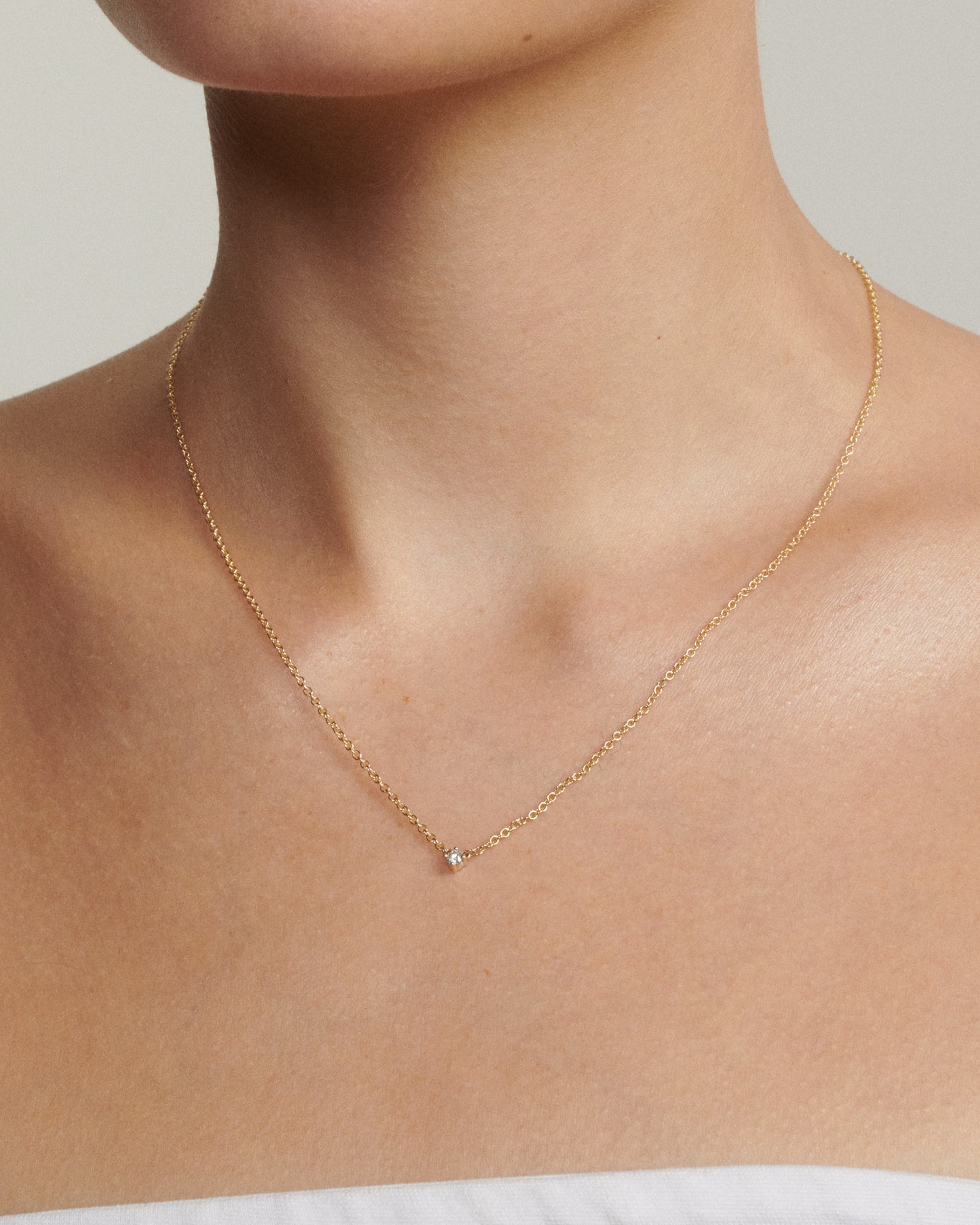 Model wears a gold chain with a tiny diamond fixed to the centre