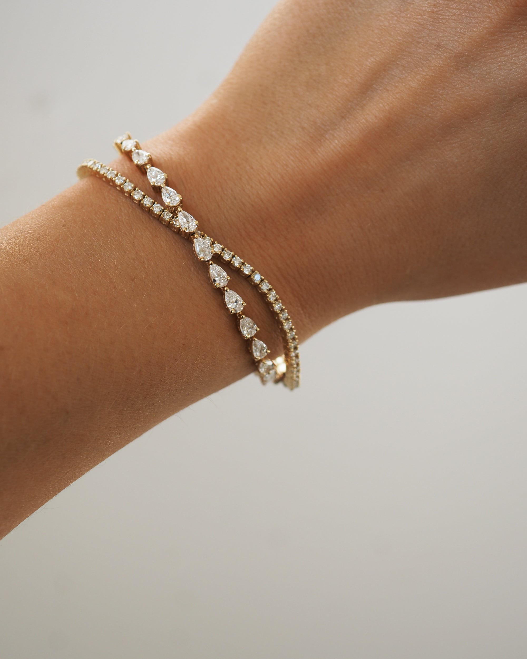 Elegant gold bracelet adorned with teardrop diamonds displayed on a wrist, showcasing luxury jewellery.