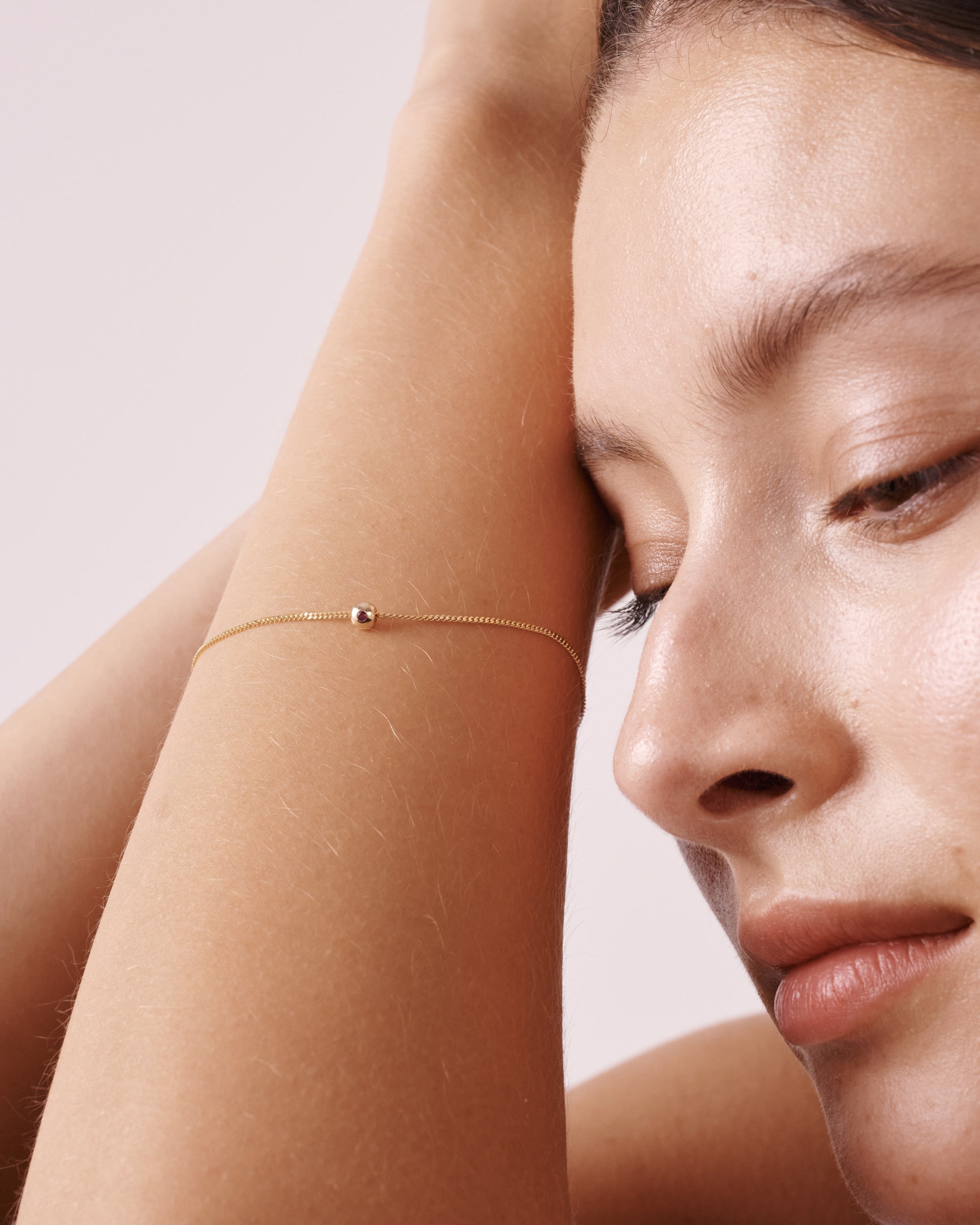 Woman wearing an elegant gold bracelet with a single small bead. The minimalist jewellery design highlights luxury and sophistication.