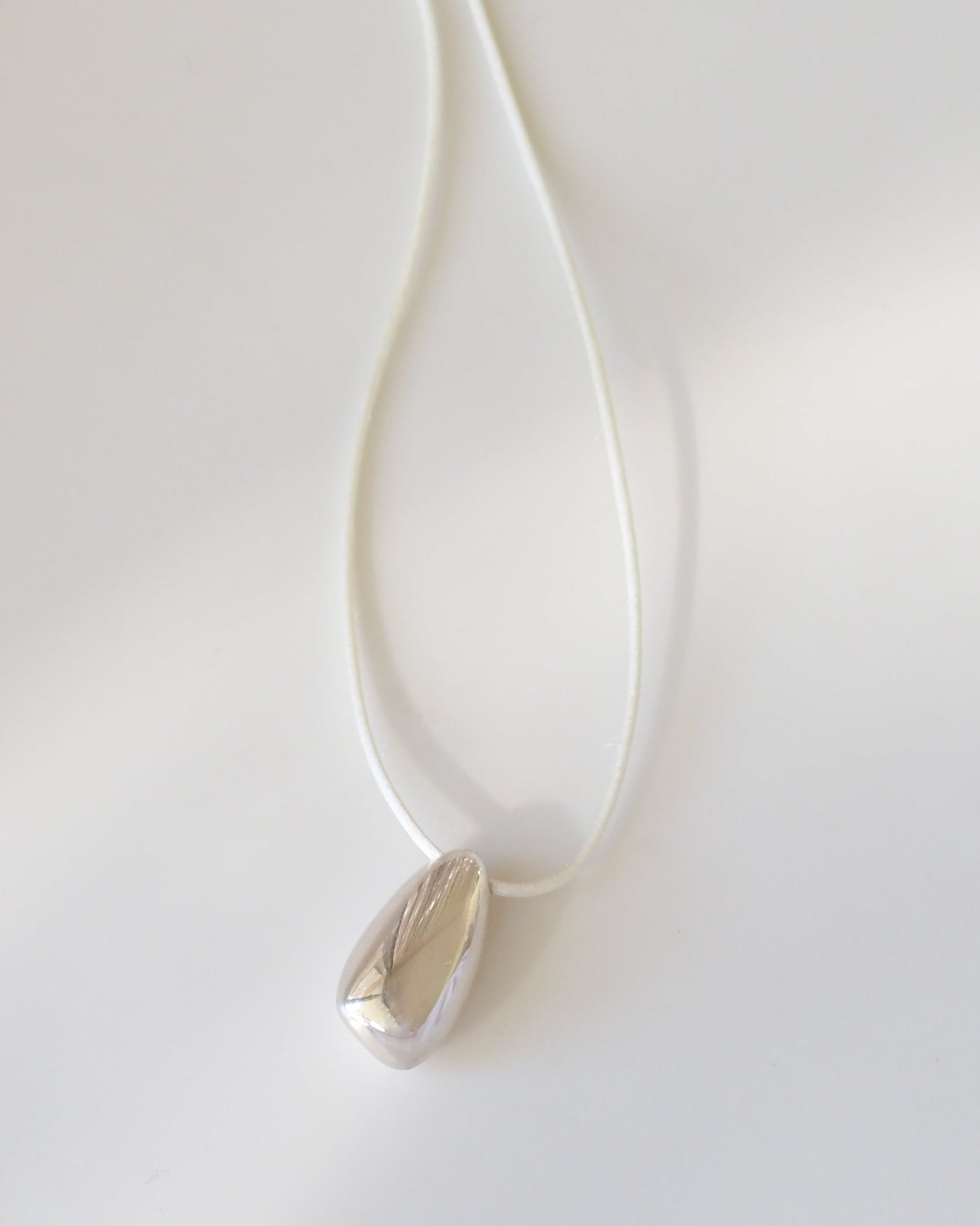 Silver necklace with a teardrop pendant on a white background [text overlay: Large Toka Pendant] [text colour: #000000]