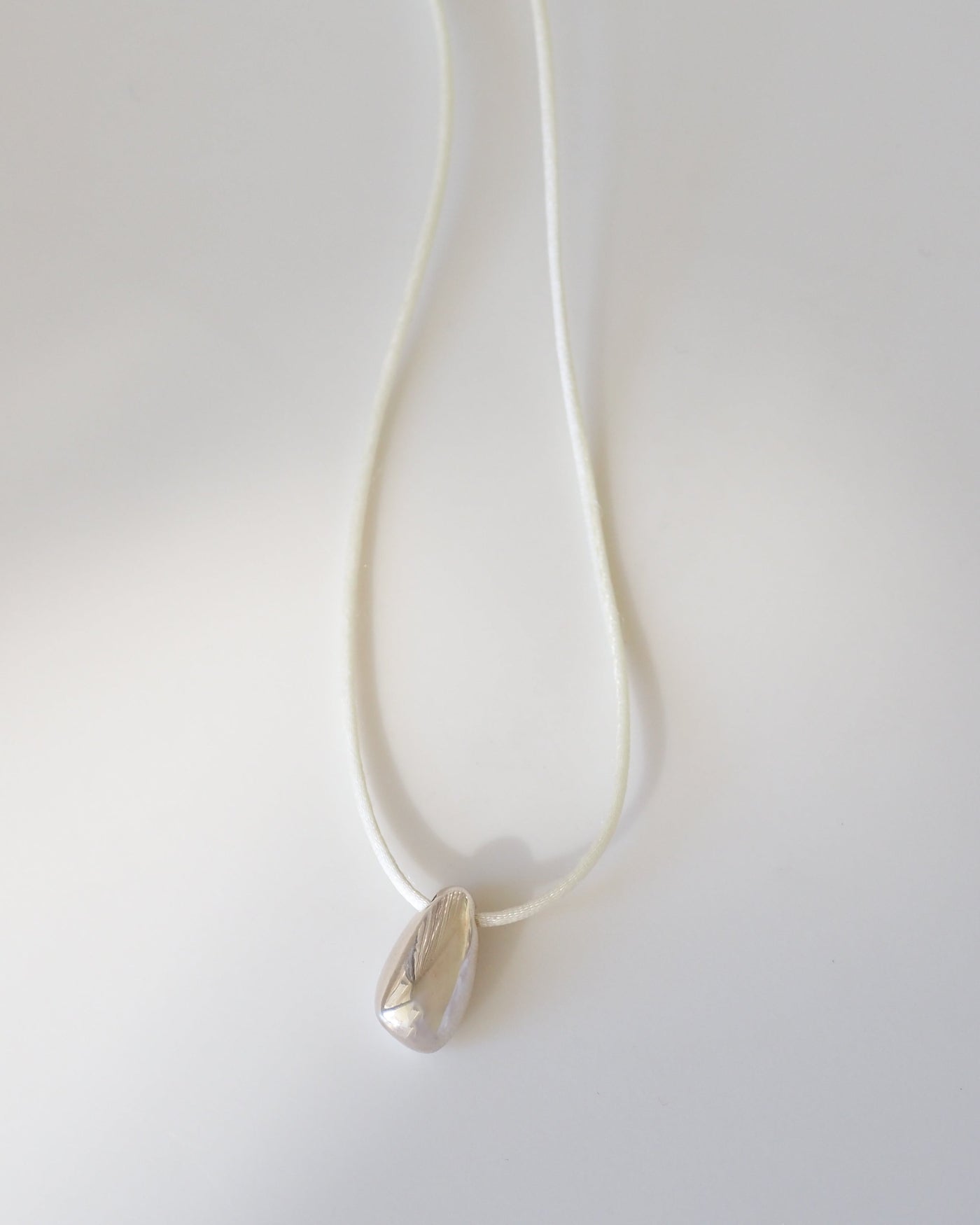Silver necklace with a pendant on a white background [text overlay: Small Toka Pendant] [text colour: #000000]